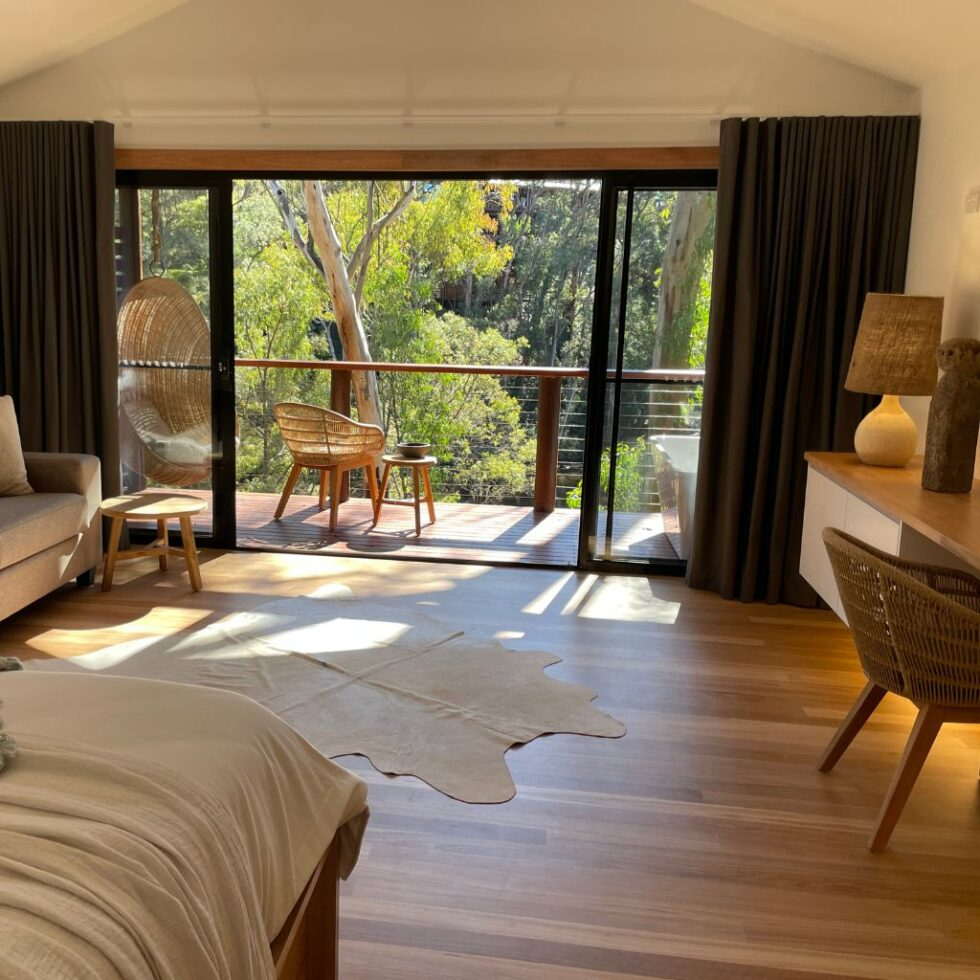 Living room with large sliding glass door leading to a balcony with outdoor seating and view of trees.