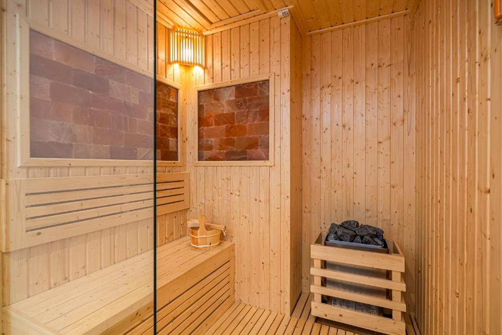 A wooden sauna room with benches, a bucket with a ladle, stone heater, and small windows.