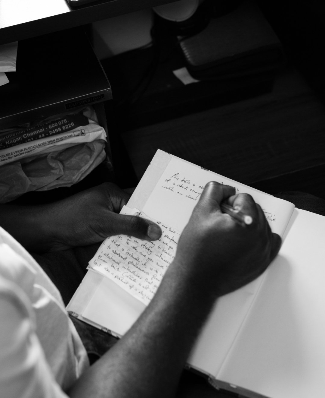 Hands writing in a notebook, in black and white