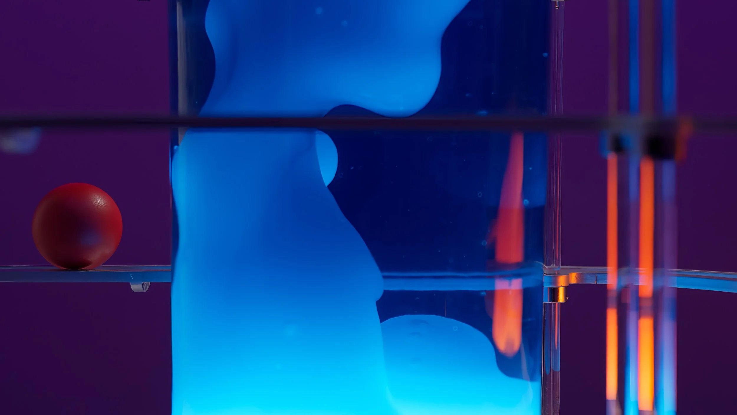 An abstract image with a red sphere on the left, a large blue form in the center, and orange vertical elements on the right, all set against a purple background with reflections.