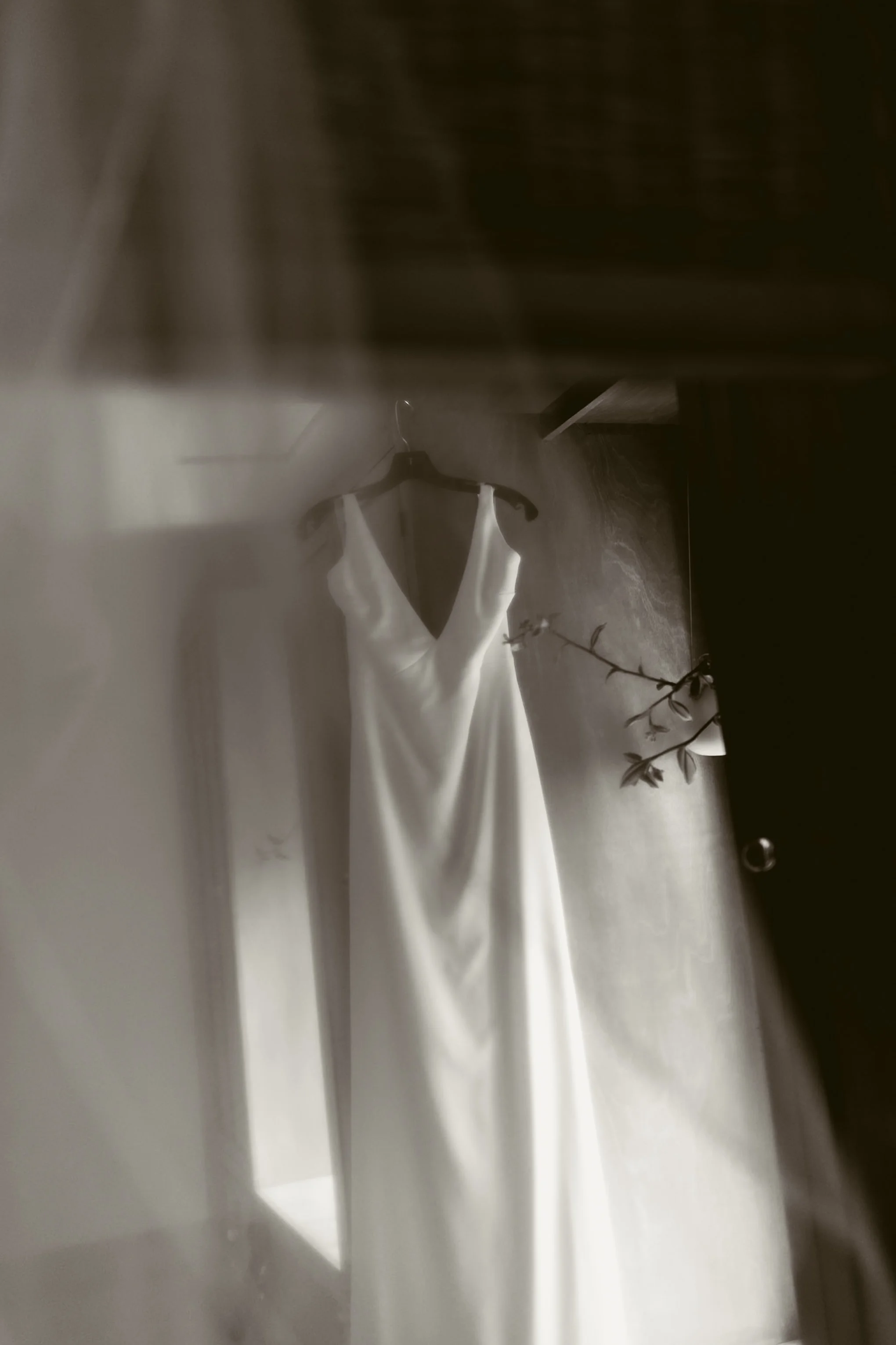 A white wedding dress hanging on a black hanger inside a dressing room.
