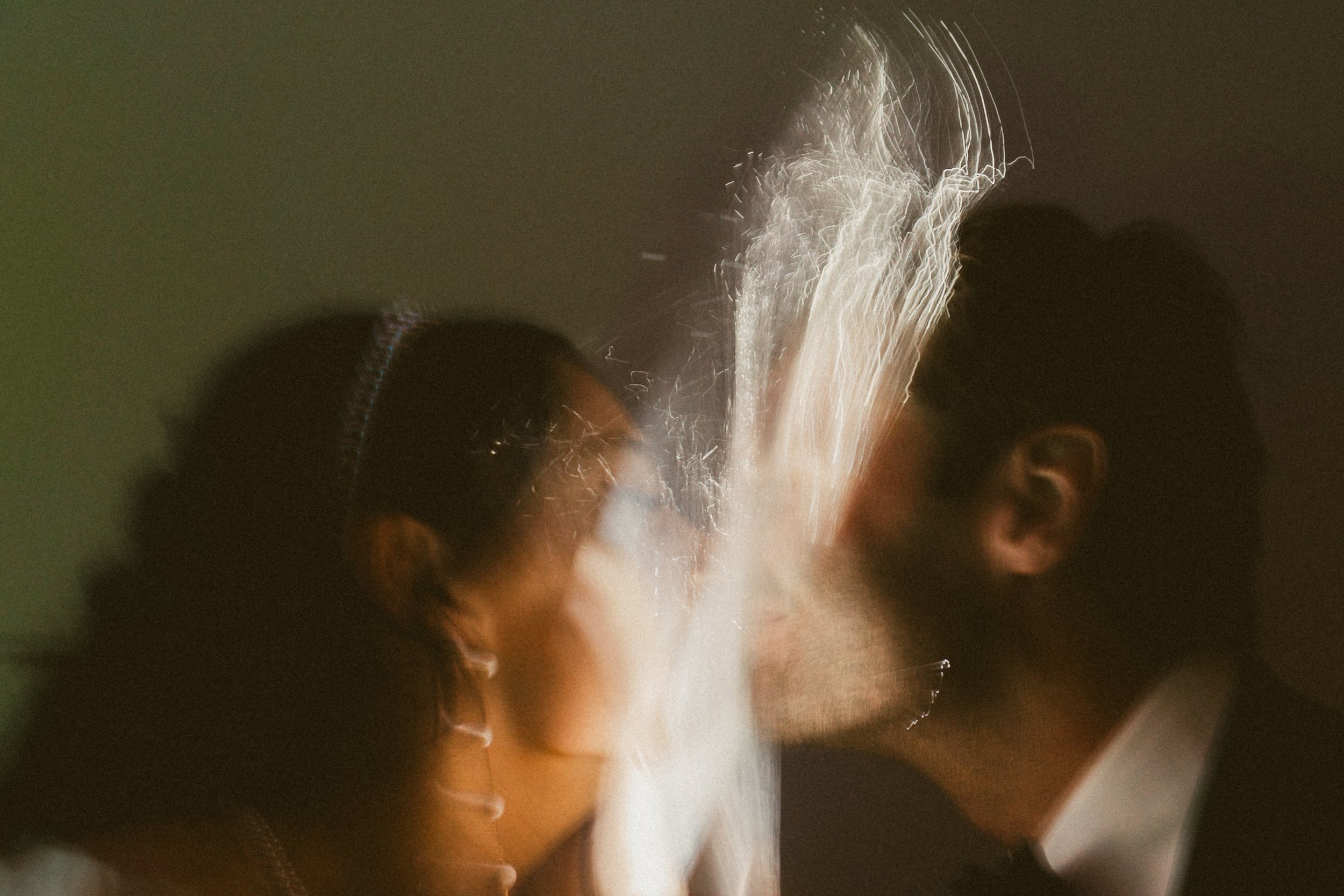 A couple facing each other during their wedding ceremony, with wedding sparkler streams crossing between them.