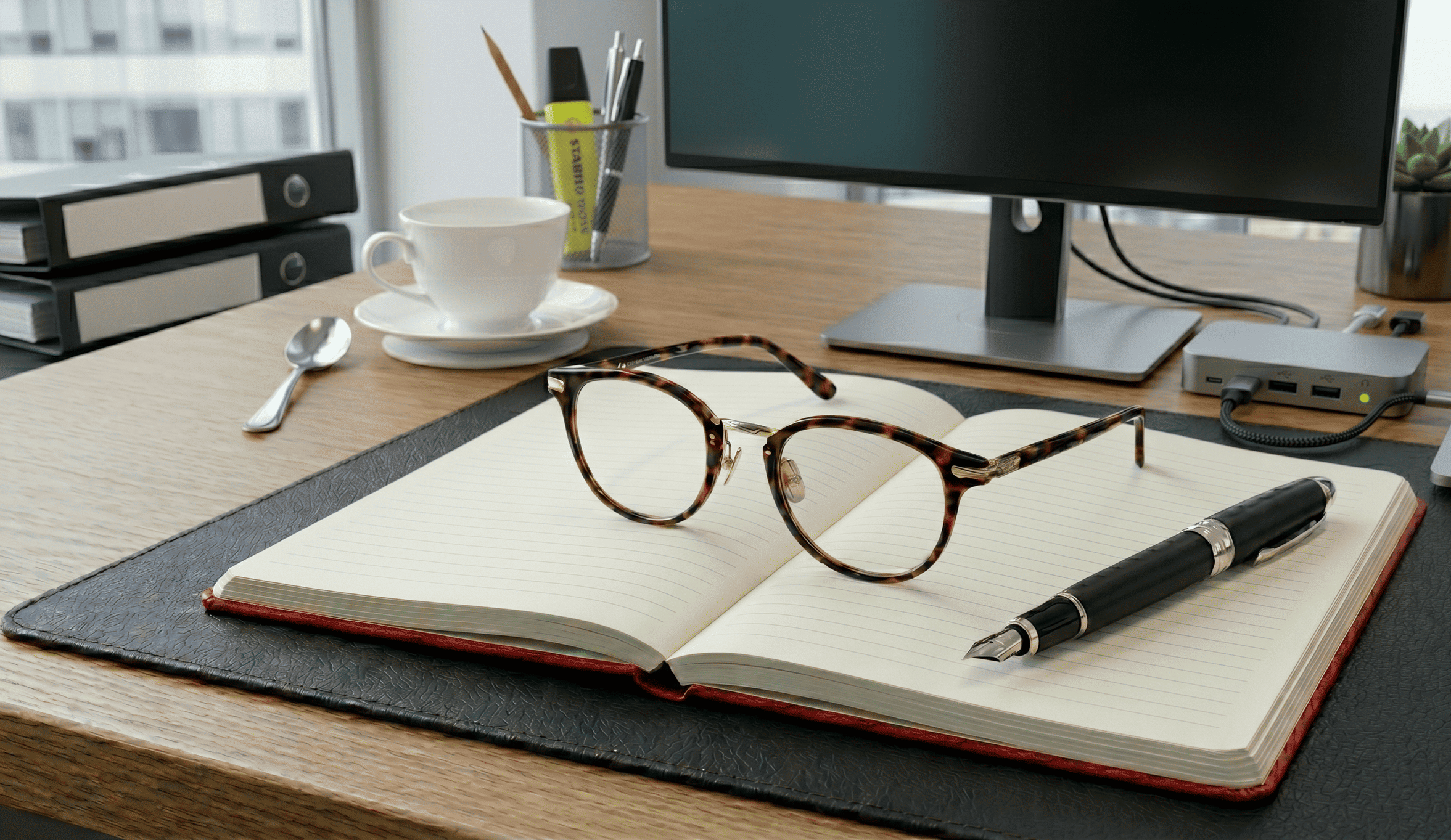 Ein aufgeraeumter Schreibtisch mit Notizbuch und Brille, ein Symbol für Klarheit im Fuehrungskraefte-Coaching fuer den oeffentlichen Dienst.