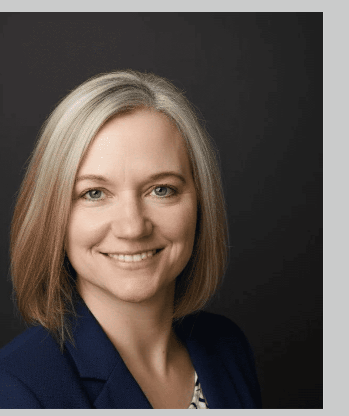 Porträt einer lachenden Andrea Wöllecke mit blonden Haaren vor schwarzem Hintergrund.