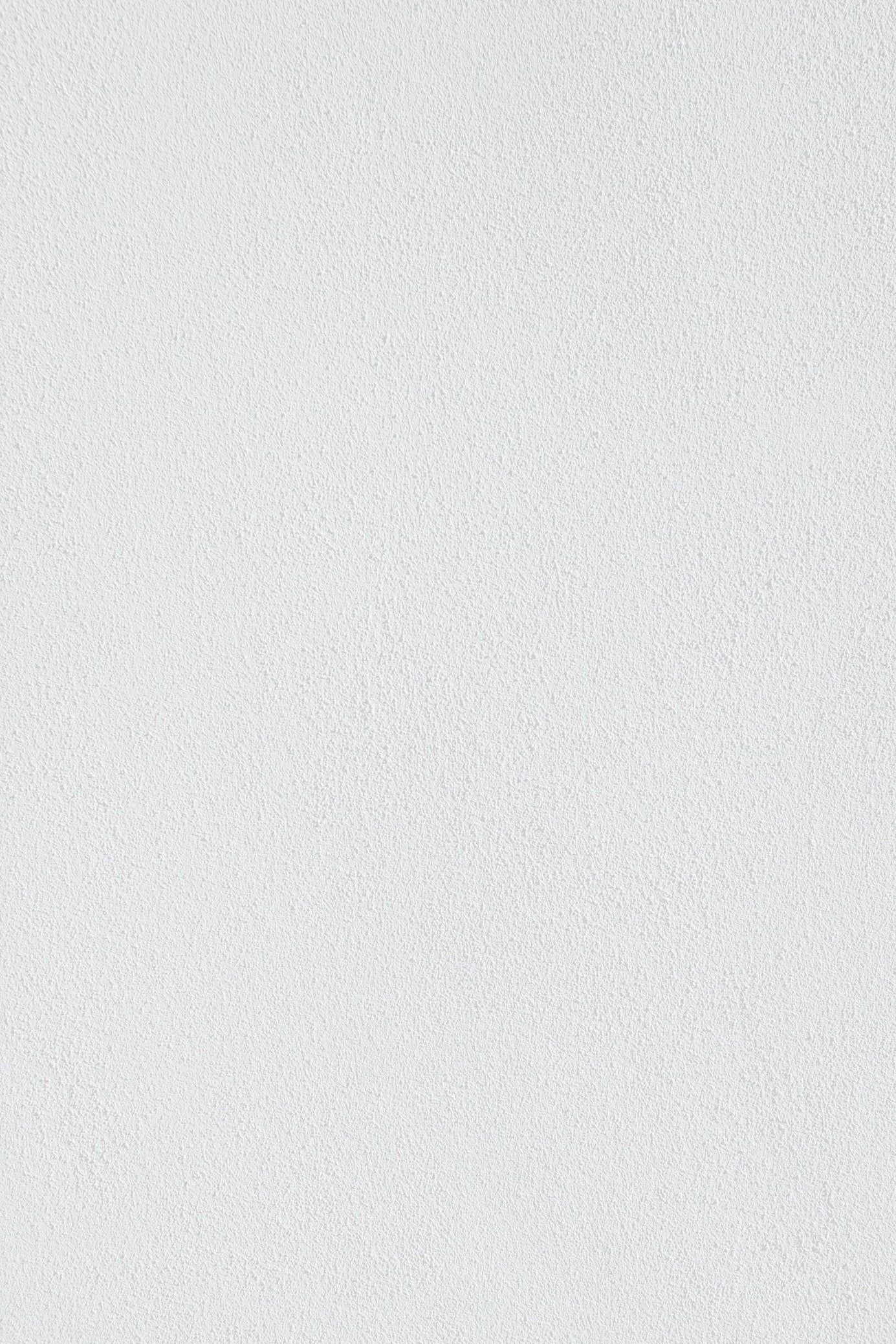 A plain white textured wall with no objects or decorations.