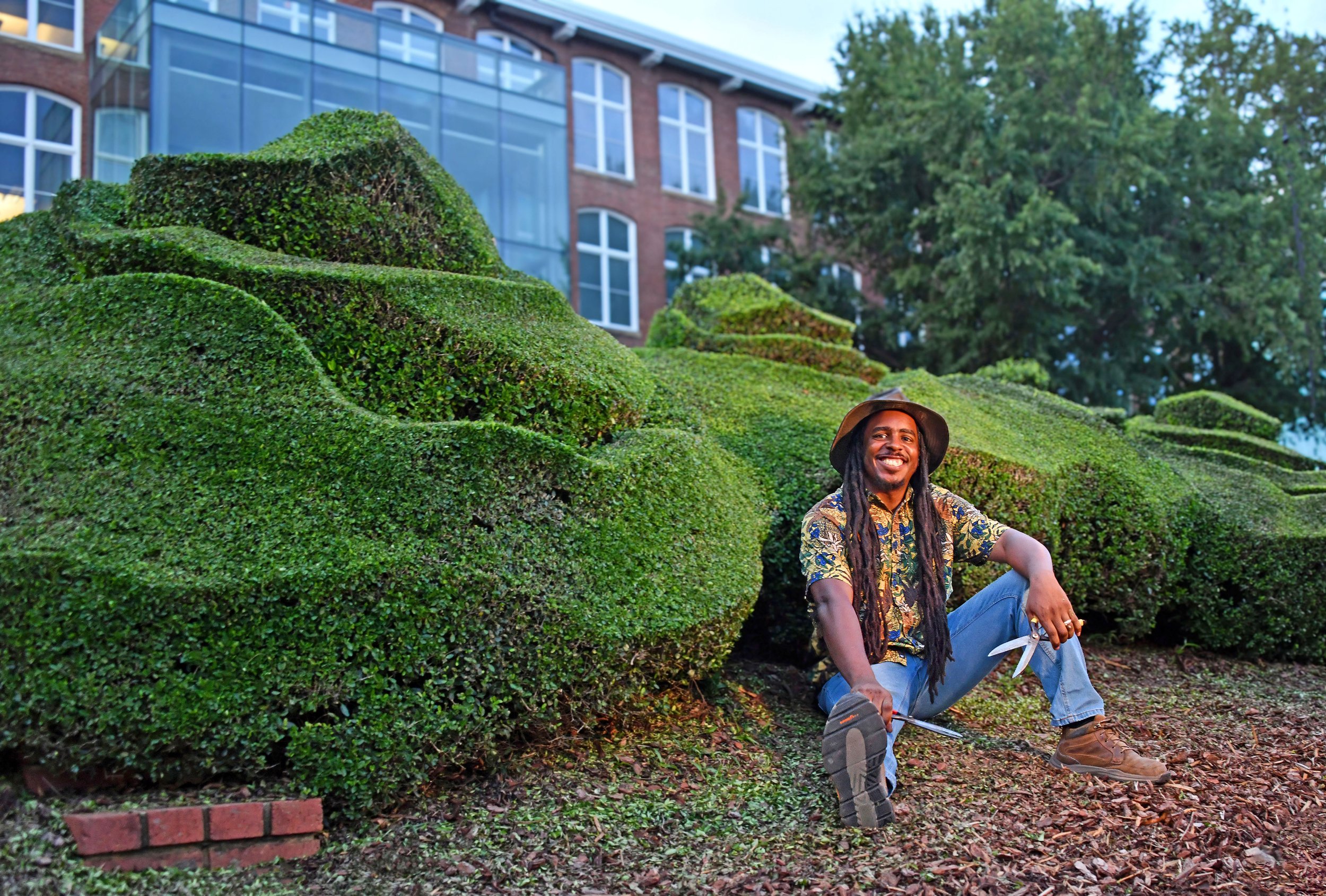 Michael Gibson sits in front of green contemporary topiary sculpture.