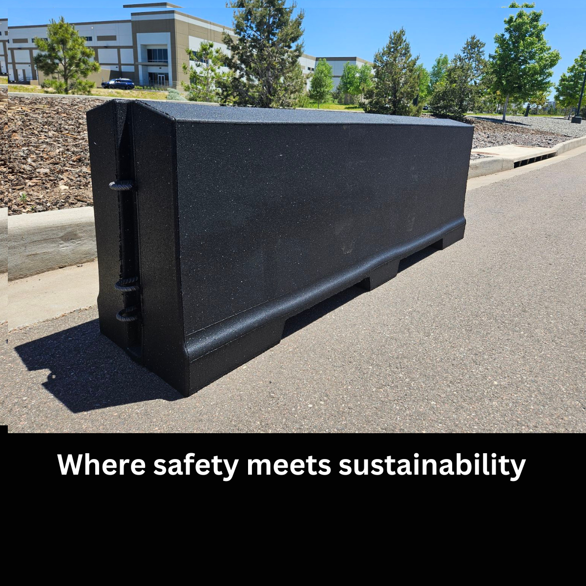 A large black compost or recycling container placed on a sidewalk outdoors with a building, trees, and a parking lot in the background on a sunny day. Captioned: 'Where safety meets sustainability.'