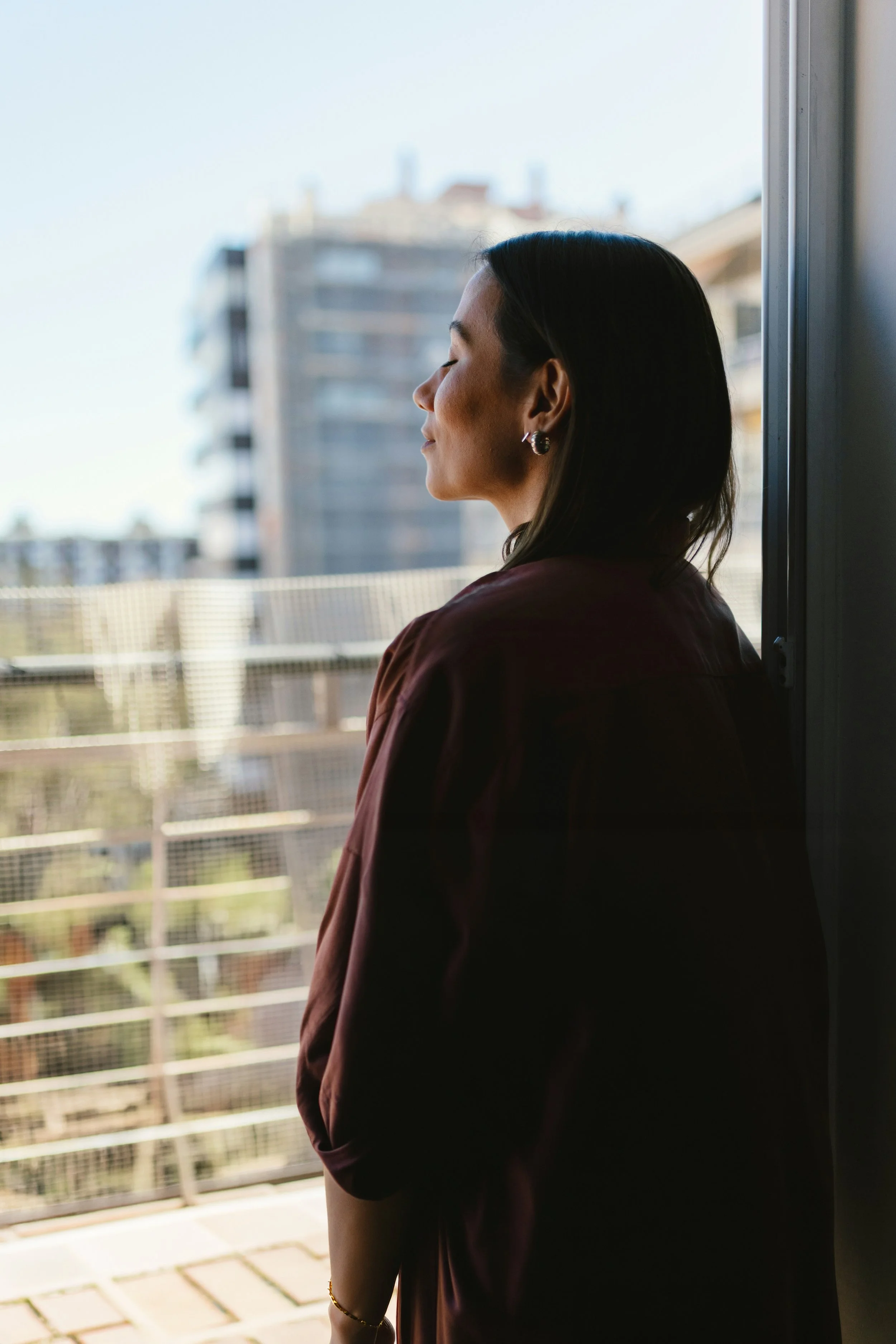 Woman taking deep breath on a doorframe, pausing before stepping through