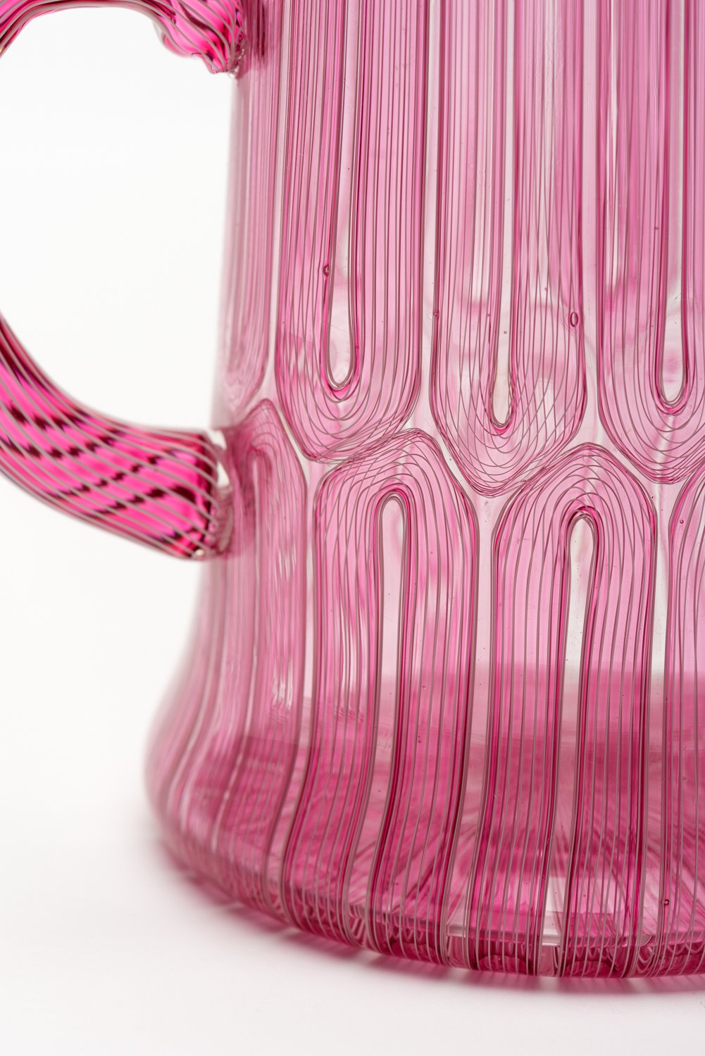 A detail of the handle of handblown pink striped mug by Xander D'Ambrosio against a white background. Image by Loam