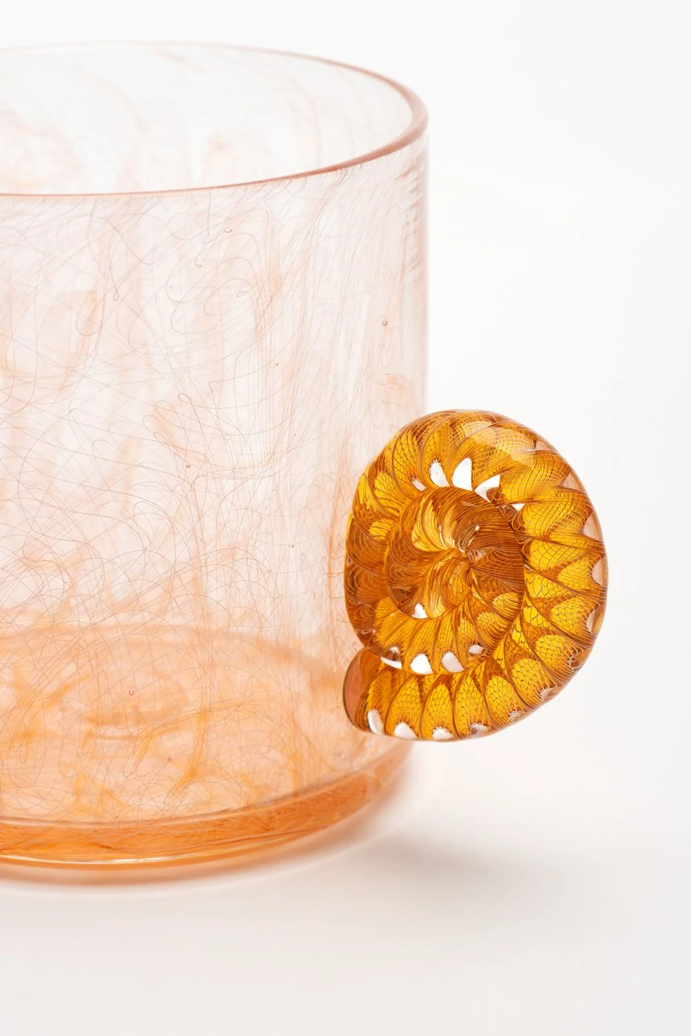 A detail of the handle of handblown orange cup by Xander D'Ambrosio against a white background. Image by Loam