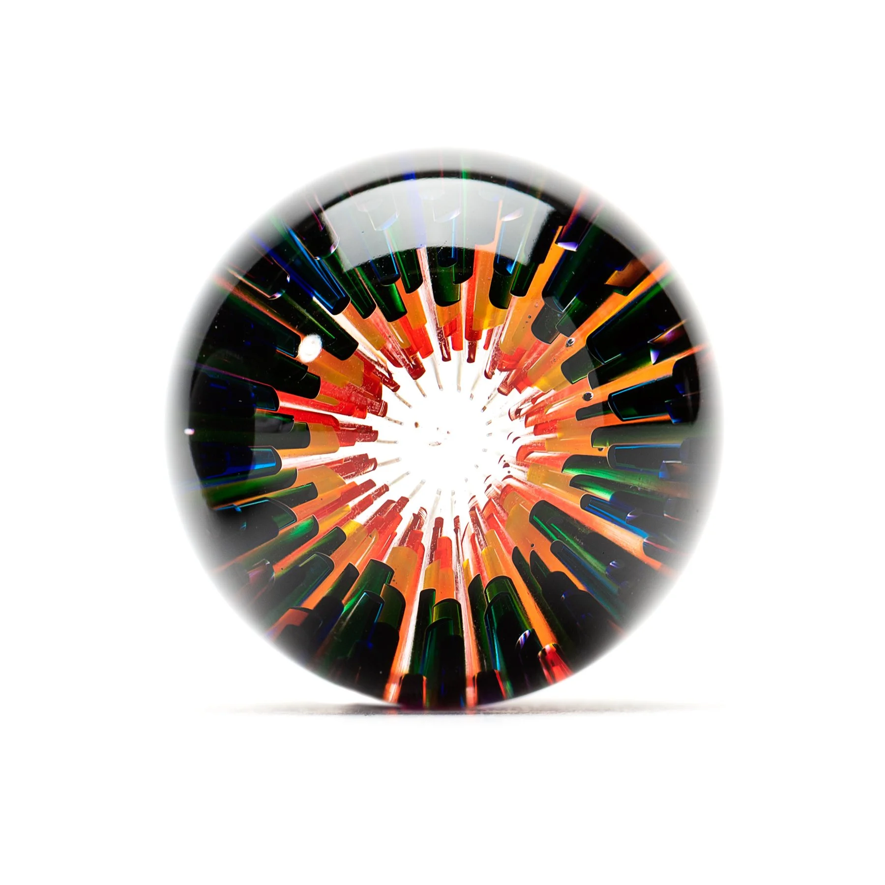 A muticolored glass marble by Xander D'Ambrosio against a white background. Image by Loam