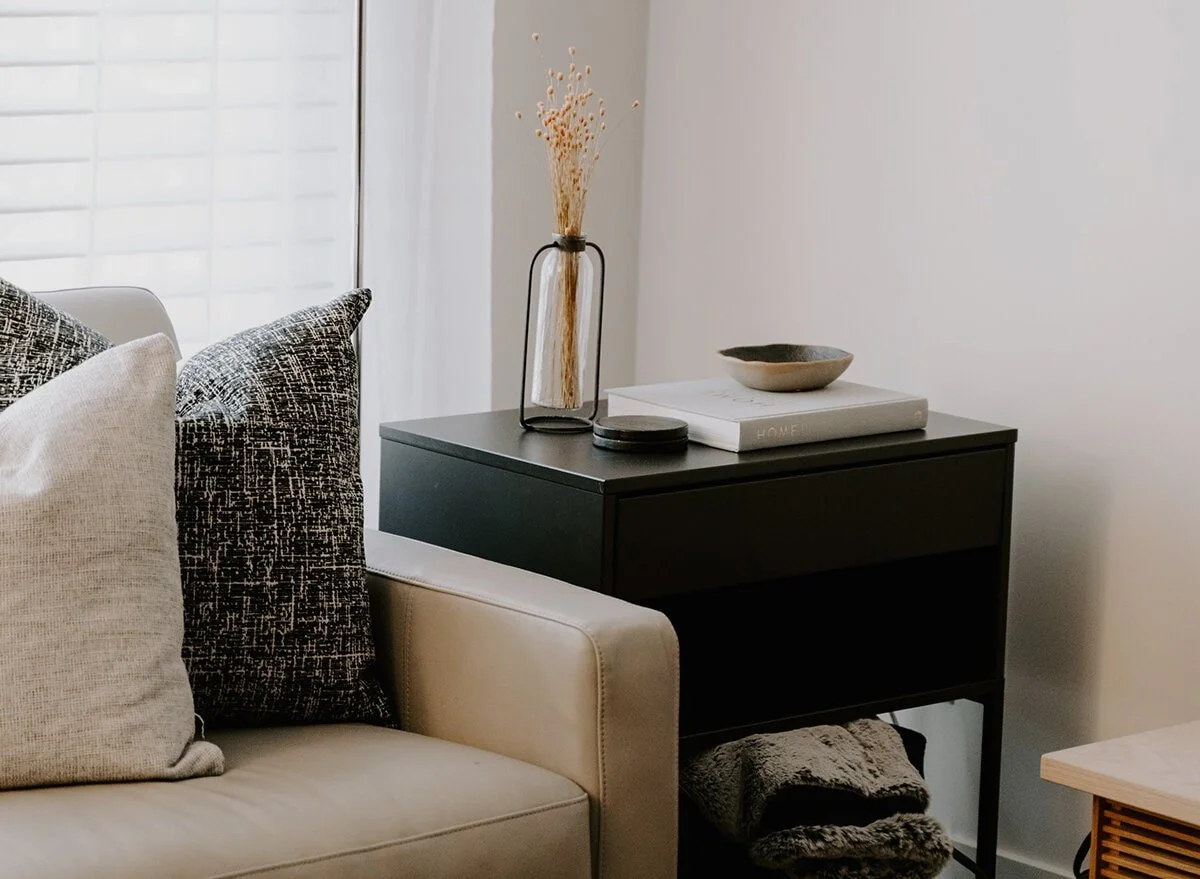 therapy office with cream couch, pillows, black end table, and a flower vase
