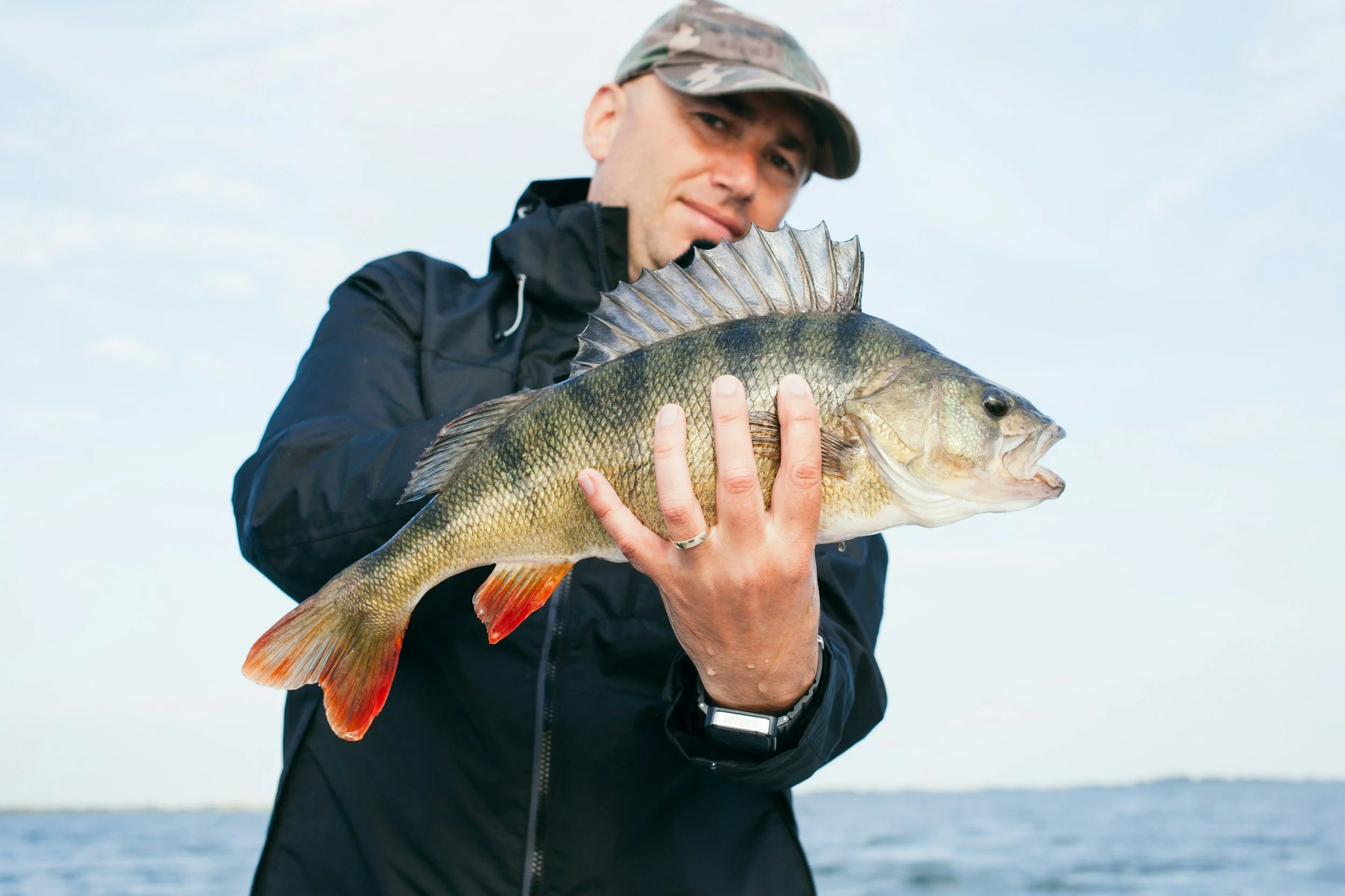 A man holding a live fish outdoors