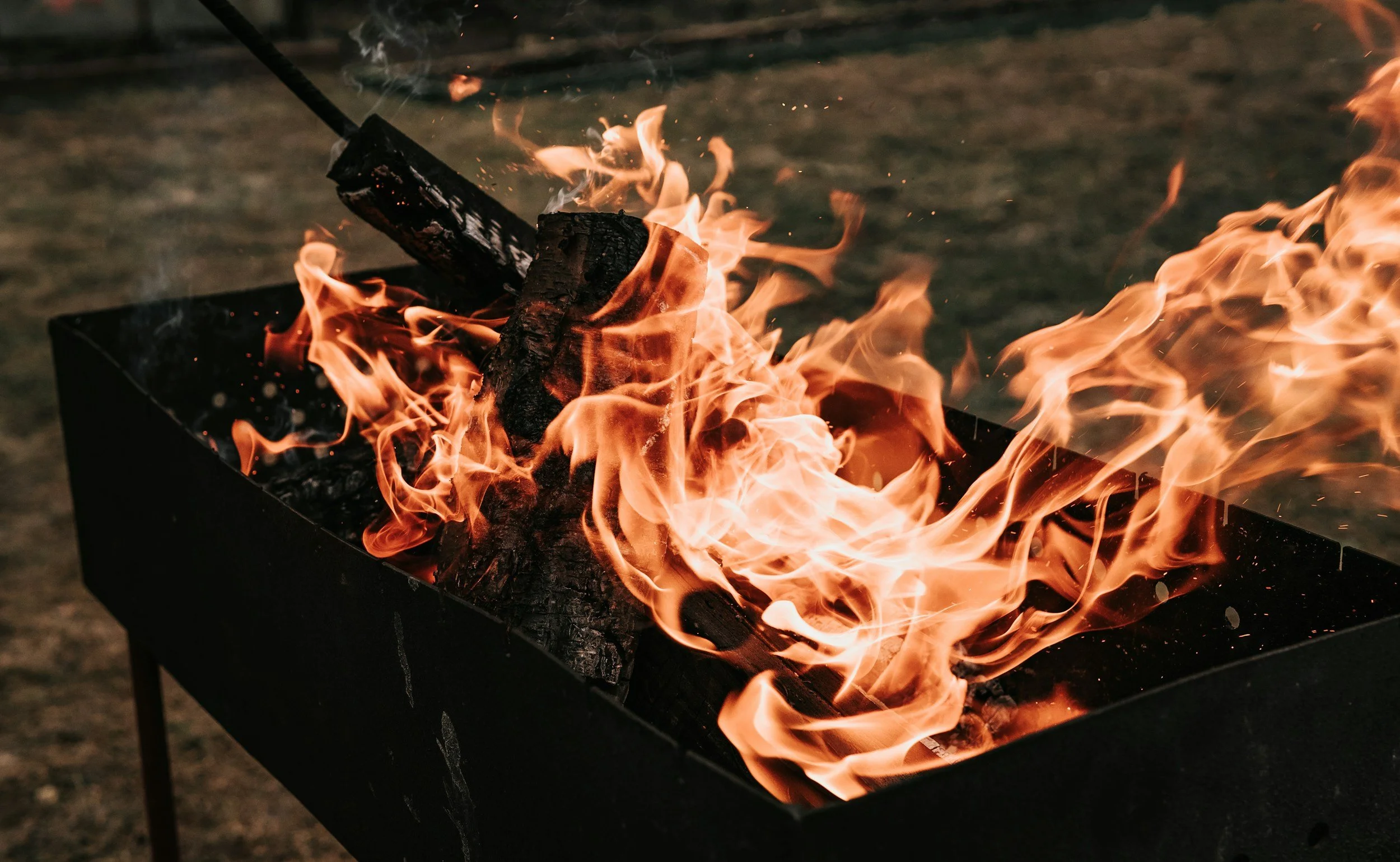 A camp-site fire pit with wooden logs burning inside