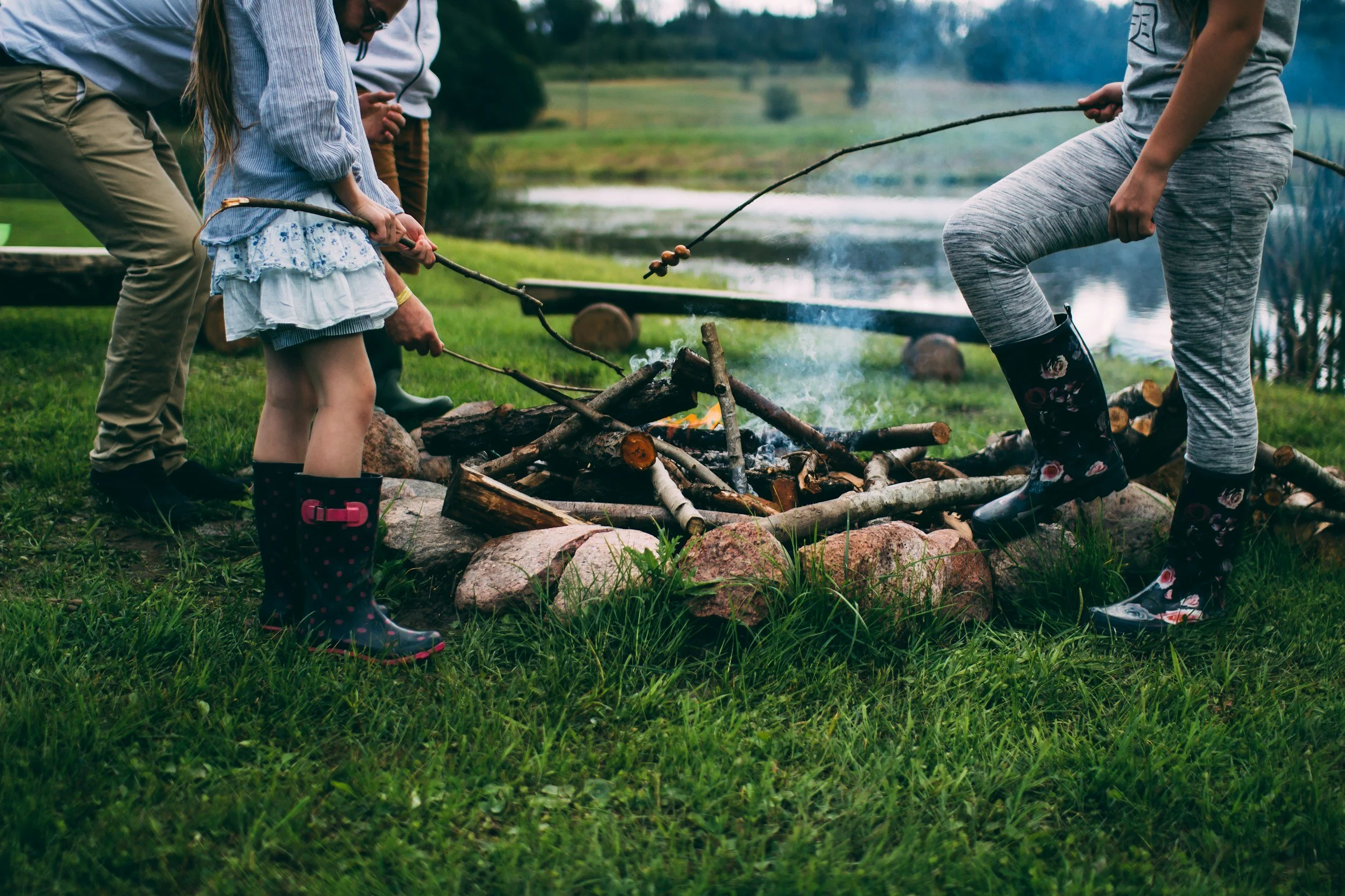 People roasting food on sticks around a campfire