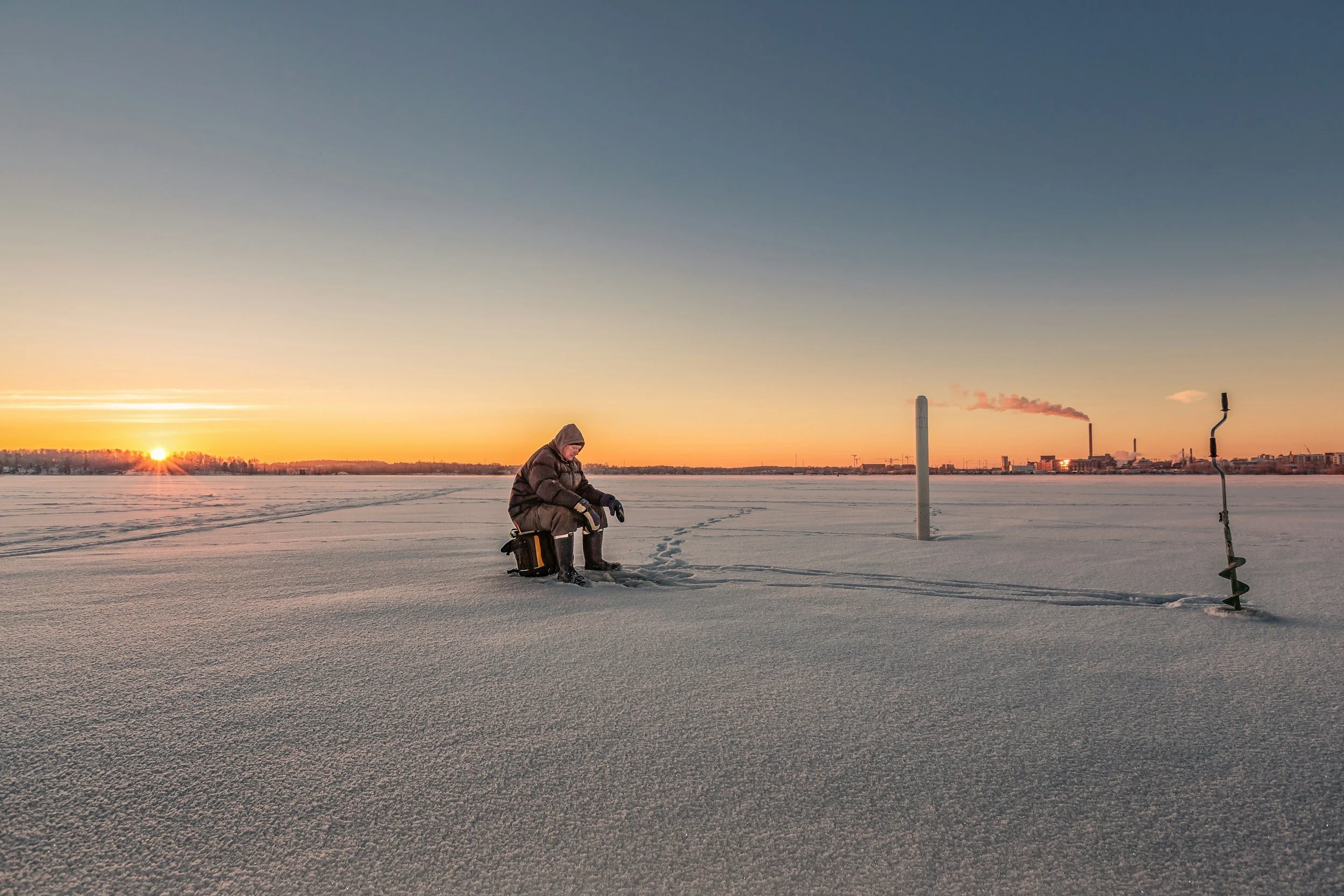 A man sitting outdoors ice fishing