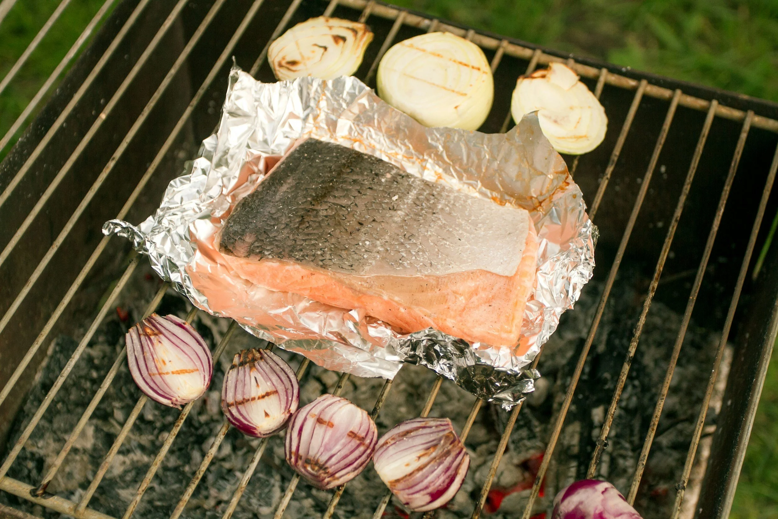 A piece of fish on a piece of foil on a grill