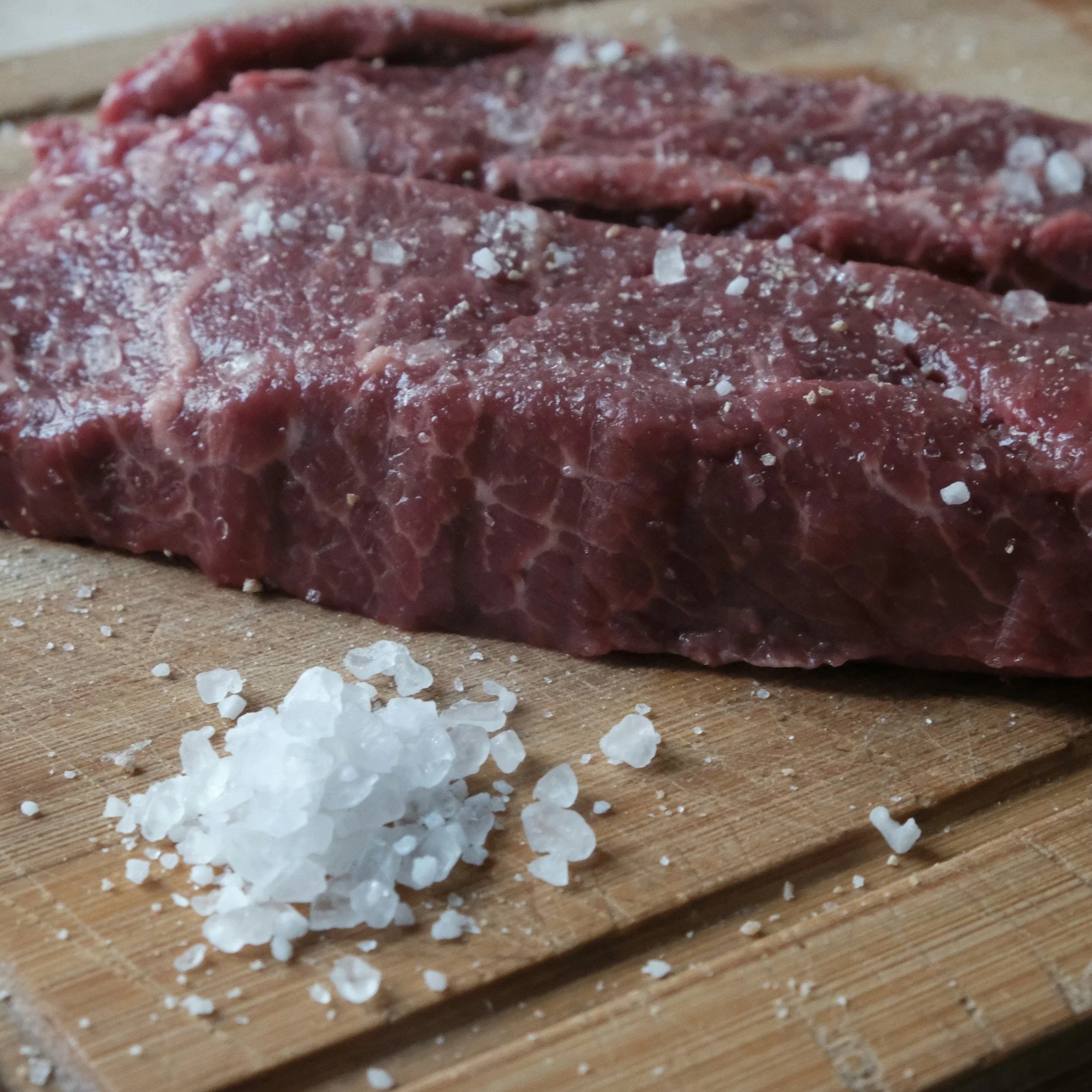 Steak next to salt on a cutting board
