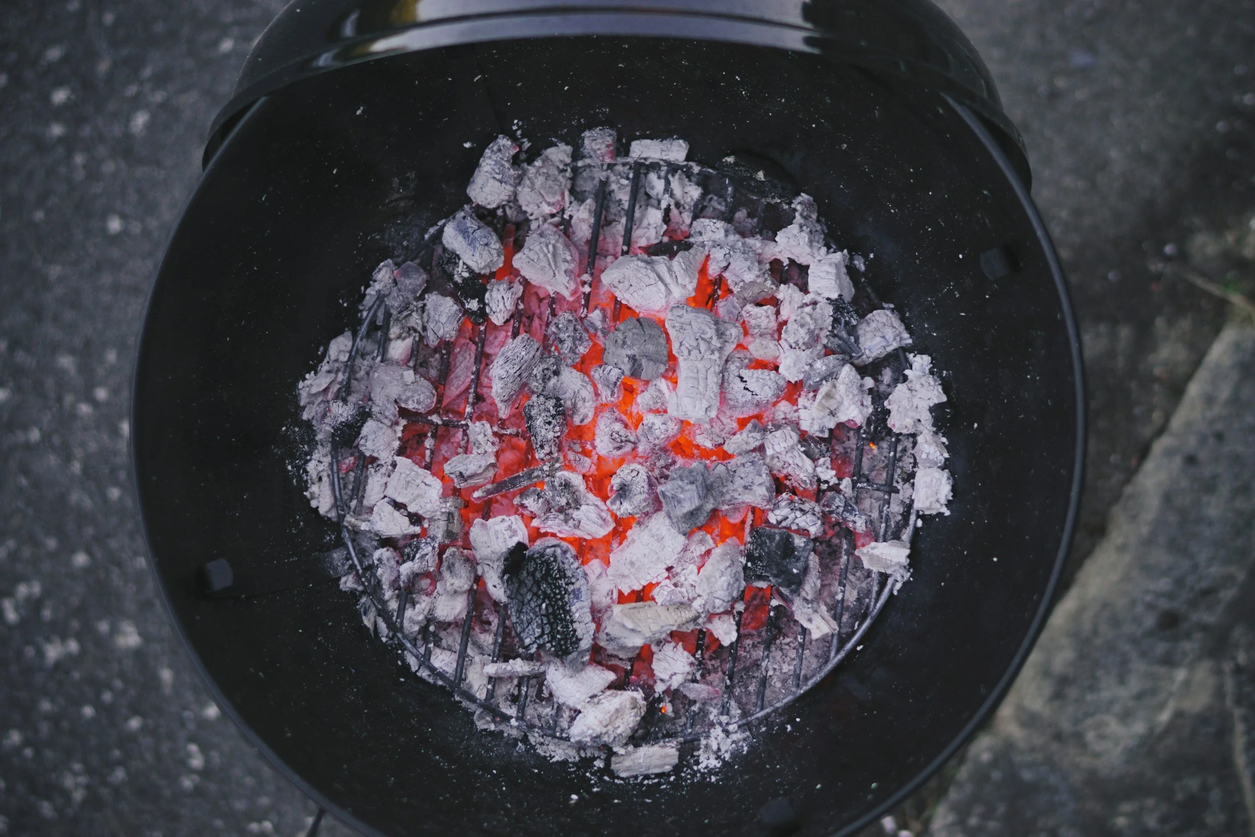 Glowing charcoal on a grill grate, viewed from above
