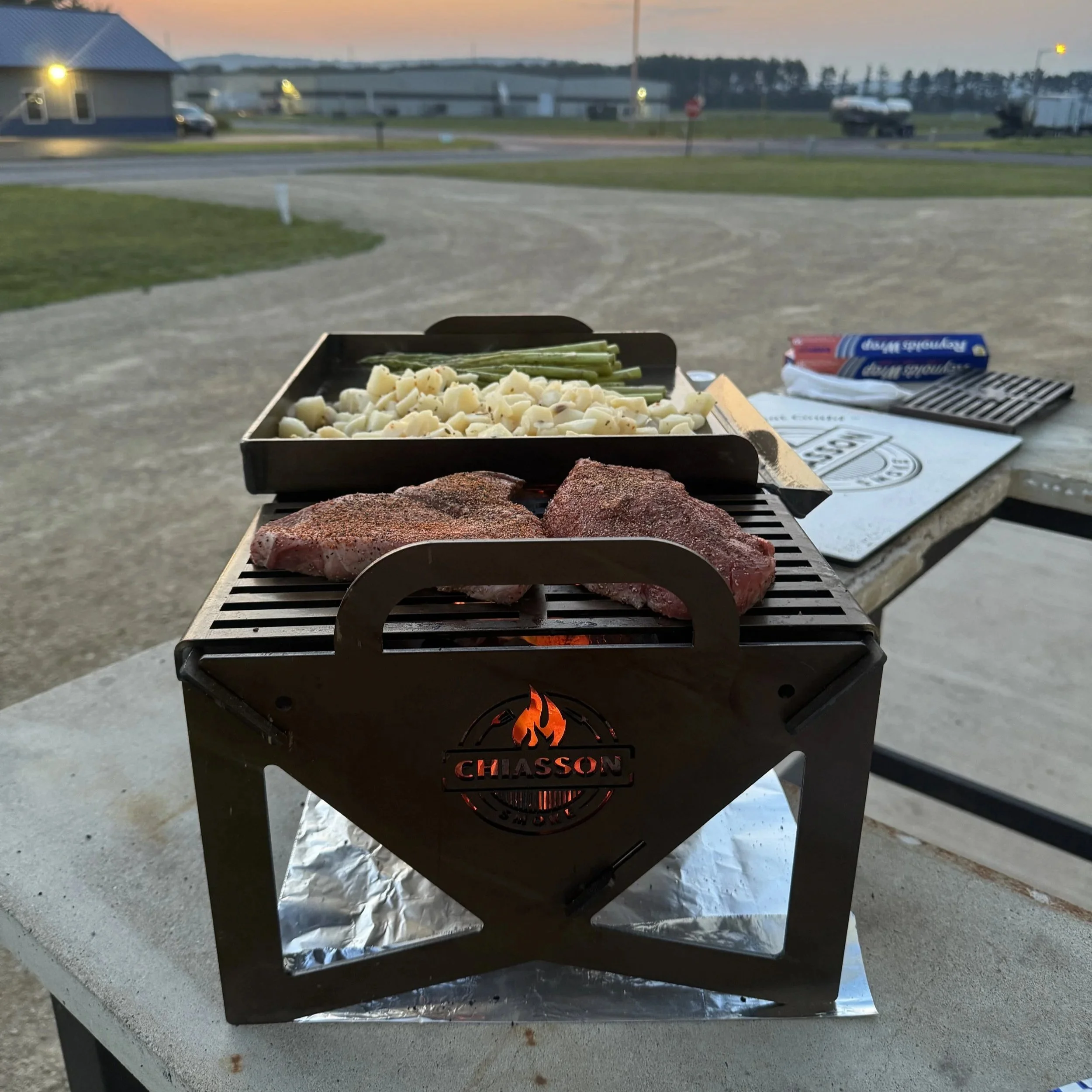 Grilling a steak dinner outside on the Chiasson Smoke Hauler Grill