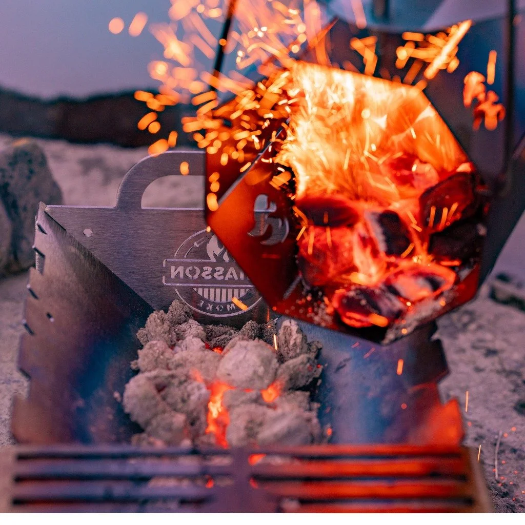 Hot coals from a charcoal chimney being poured into a portable Hauler grill