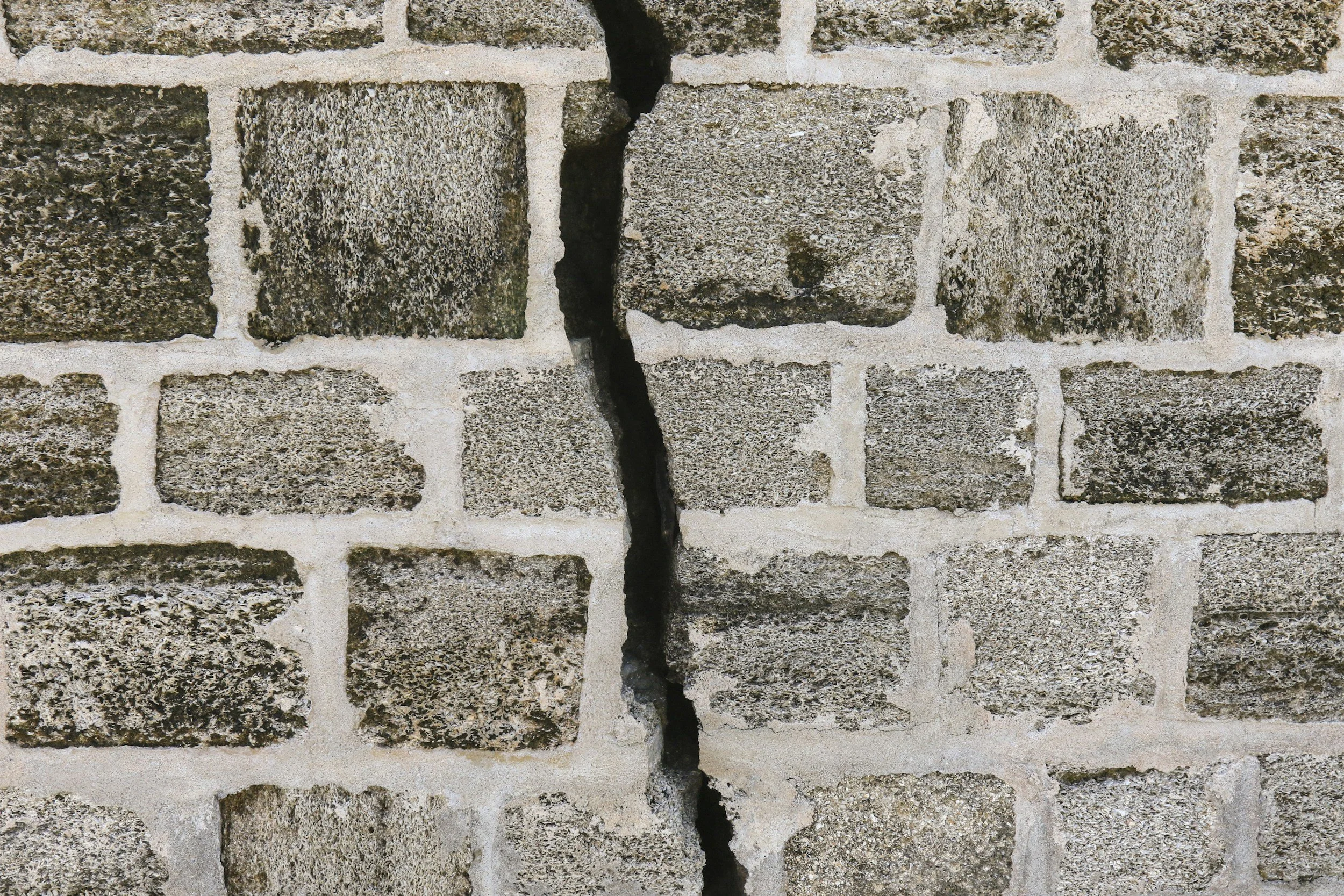A crack in a brick wall representing feeling broken but not falling apart.