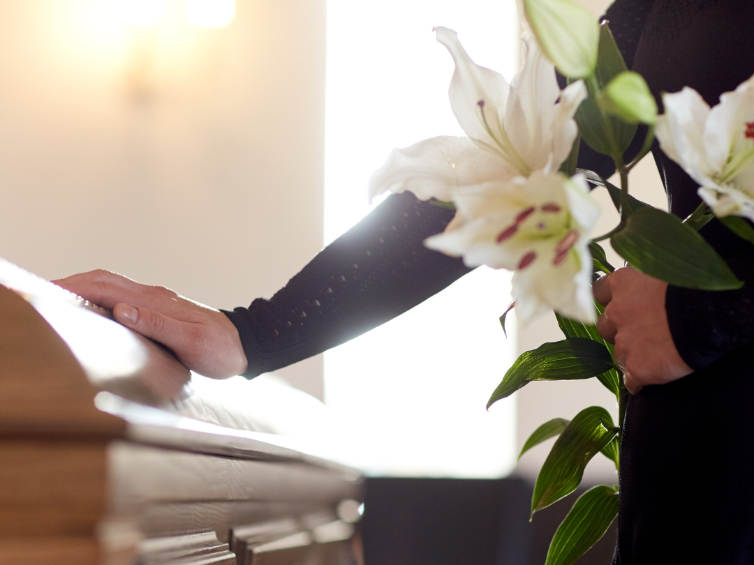 Casket and flowers representing probate and estate planning decisions families face after a death in North Carolina.