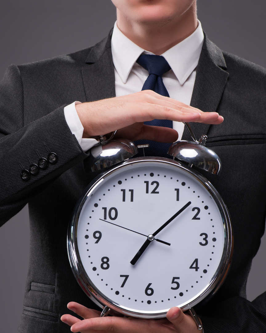 Man in business attire holding a large clock, symbolizing the 9 to 12 month probate timeline in North Carolina.