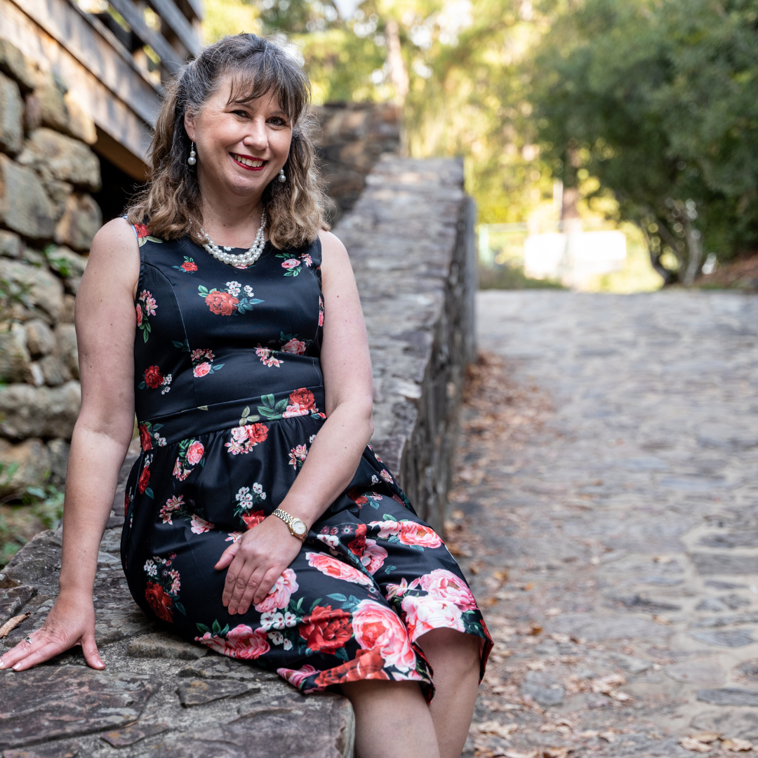 Kristen Mackintosh, The Happy Lawyer sitting on a stone rail in Garner where she assists clients with estate planning