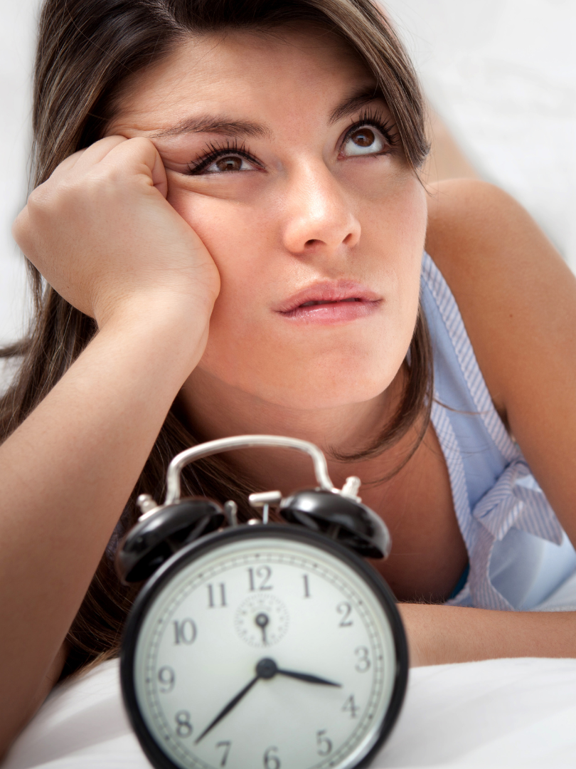 Woman resting her head near an alarm clock, representing frustration and waiting during the North Carolina probate process.