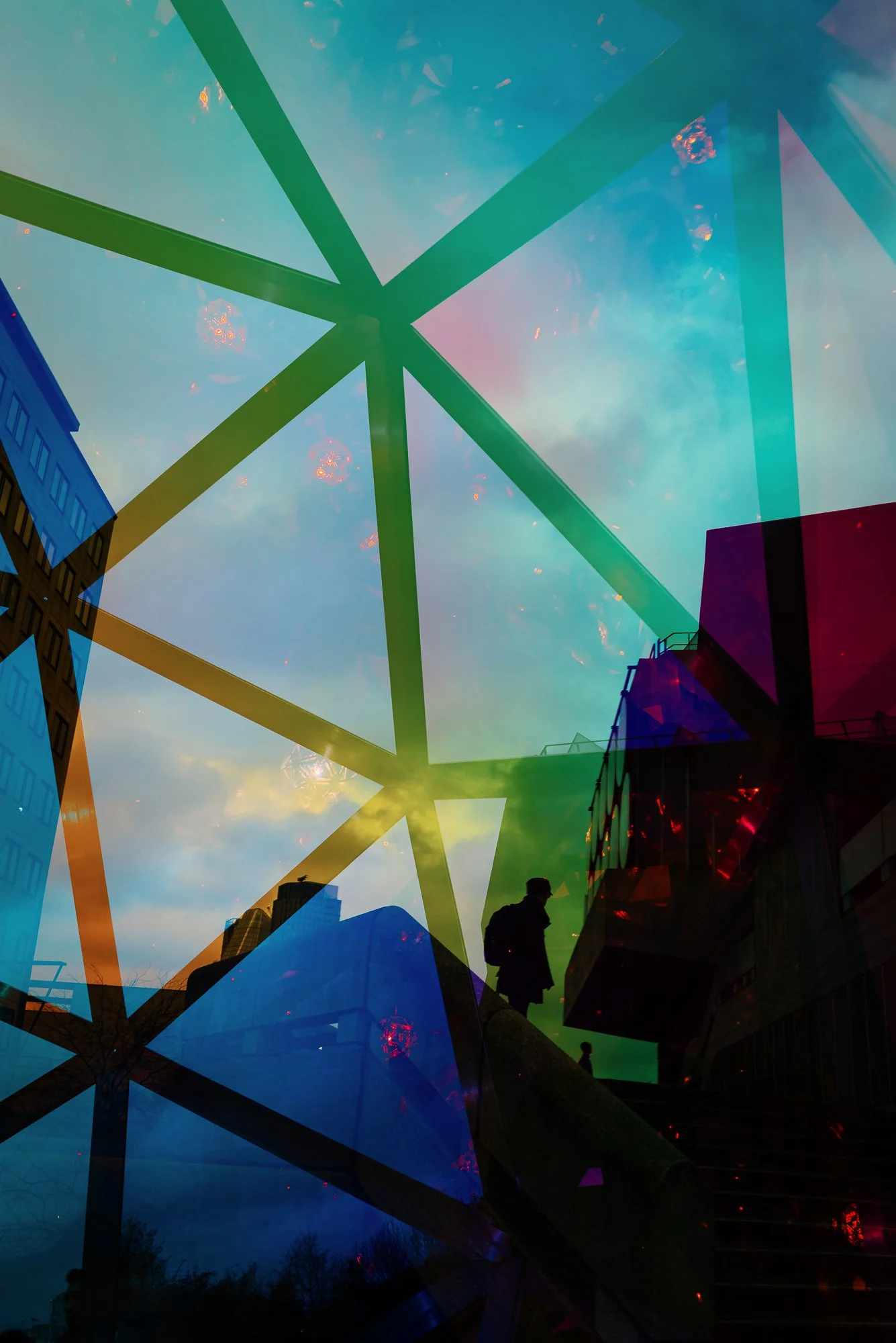 Reflective glass panels with colorful lighting and silhouettes of people walking outside buildings.