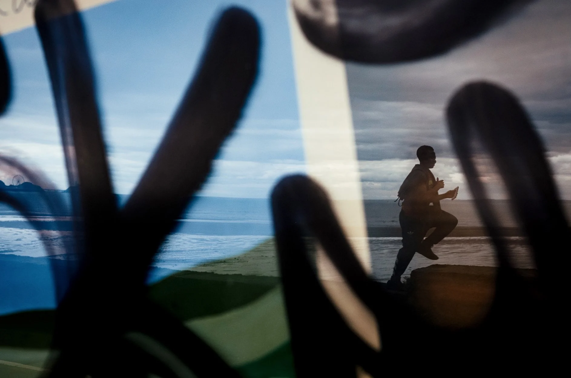 A person running on the beach during sunset, seen through a window or glass with black framing or spots in the foreground.