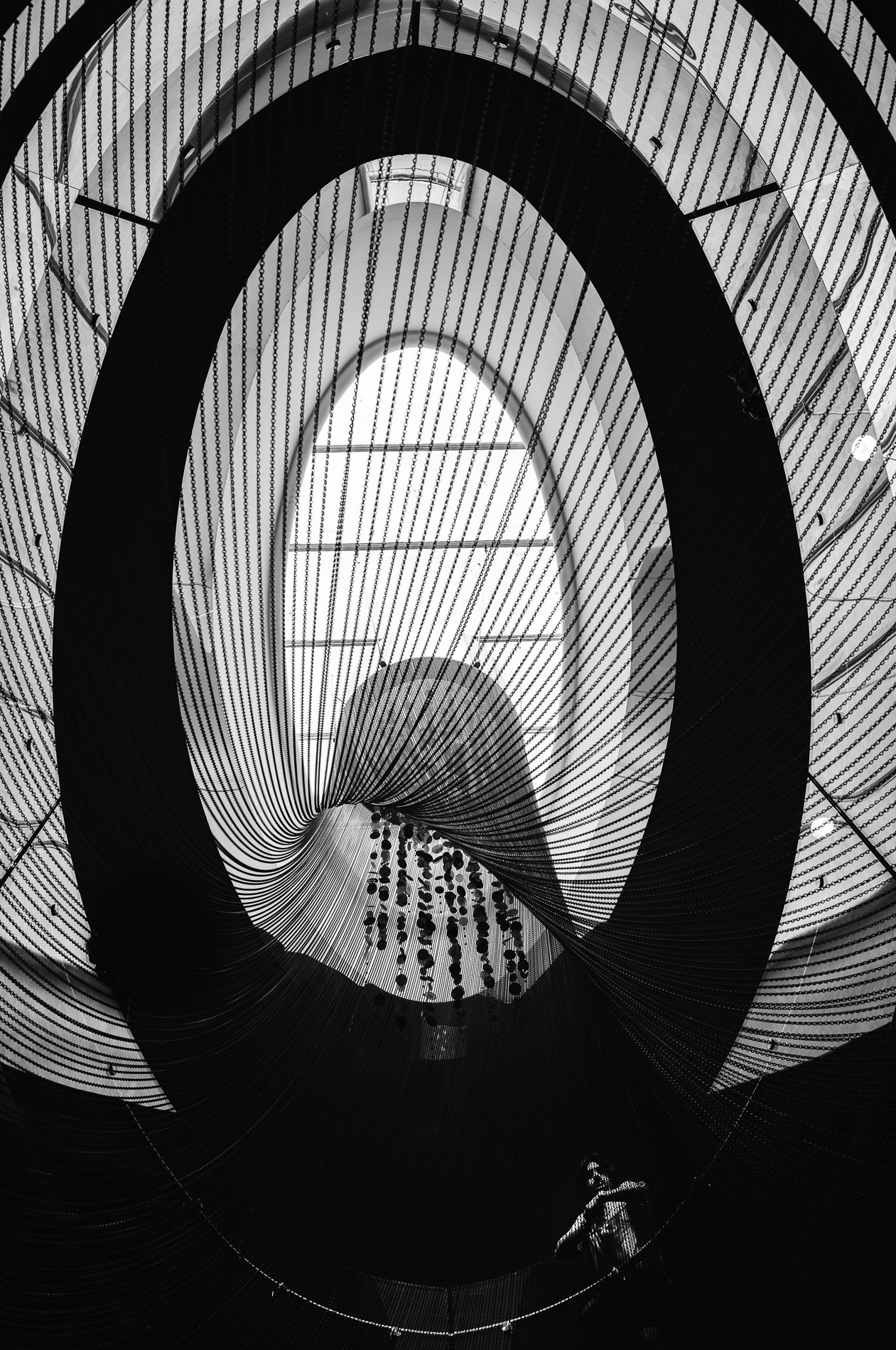 Interior view of a spiral staircase with black and white design, featuring hanging lights and railings.