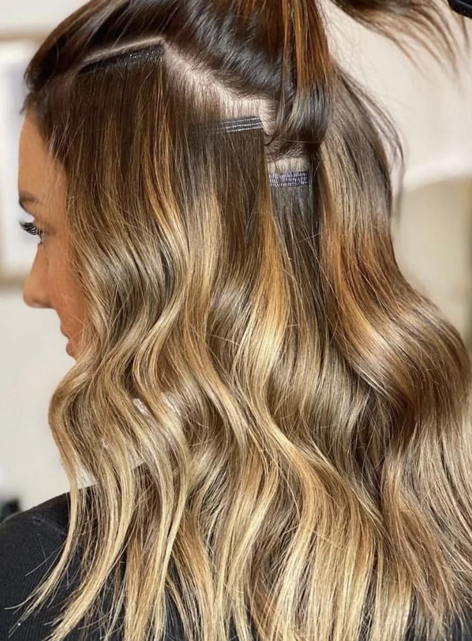 Close-up of a woman's wavy, blonde-highlighted hair sectioned with hair clips.