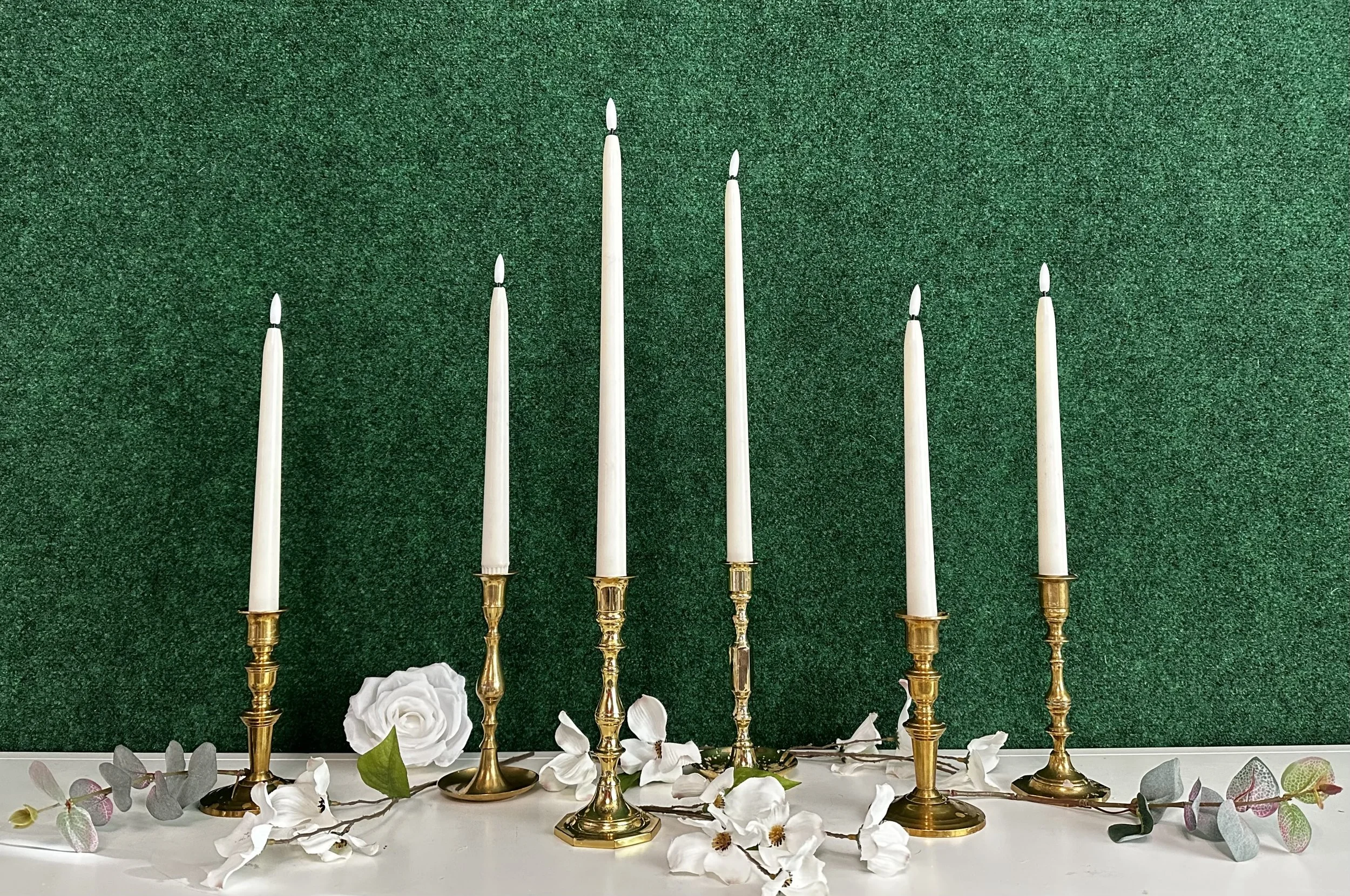 Mixed vintage brass taper candle holders with tall ivory tapers for romantic wedding centerpiece rentals in Tri-Cities, WA.