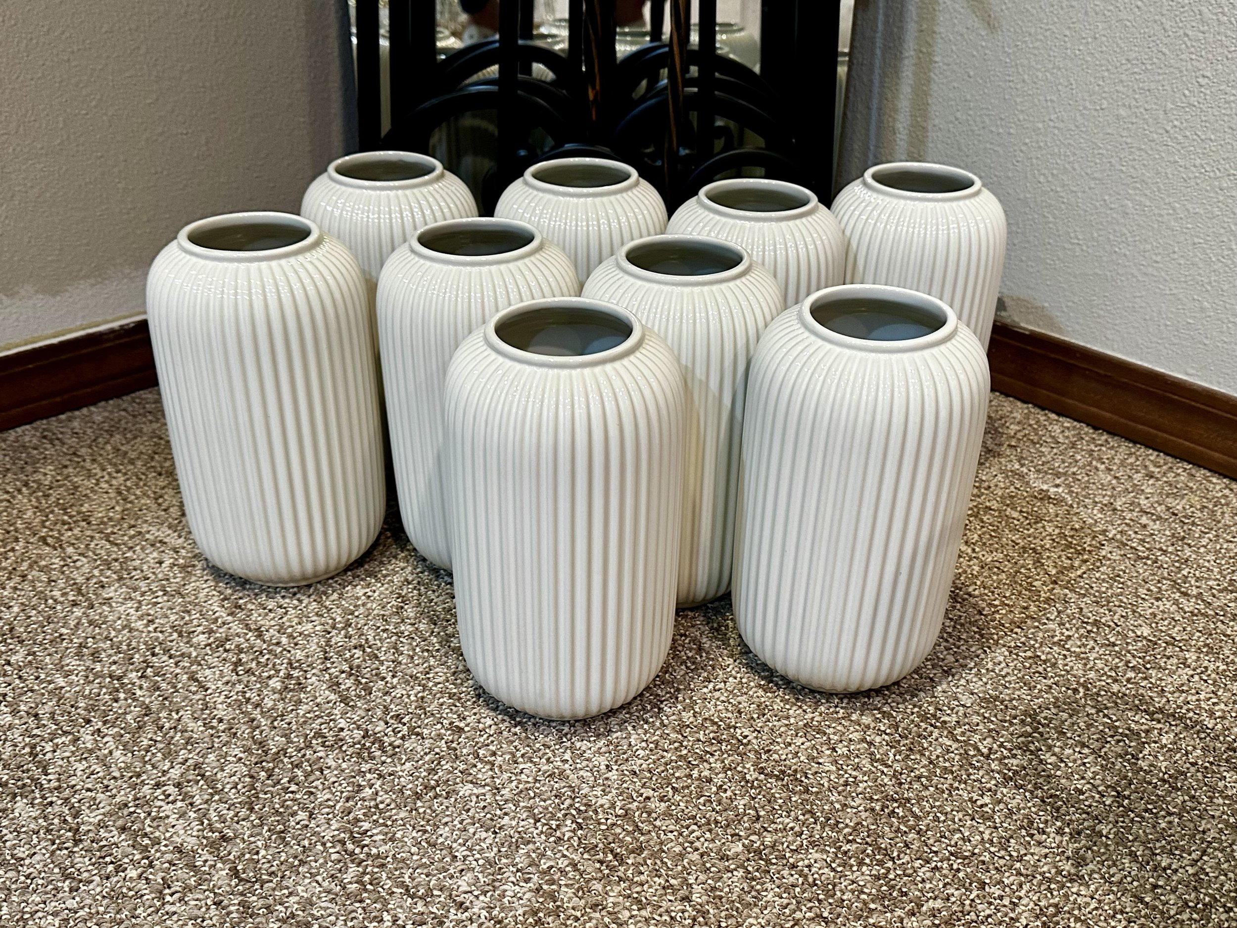 White ribbed ceramic vases on beige carpet