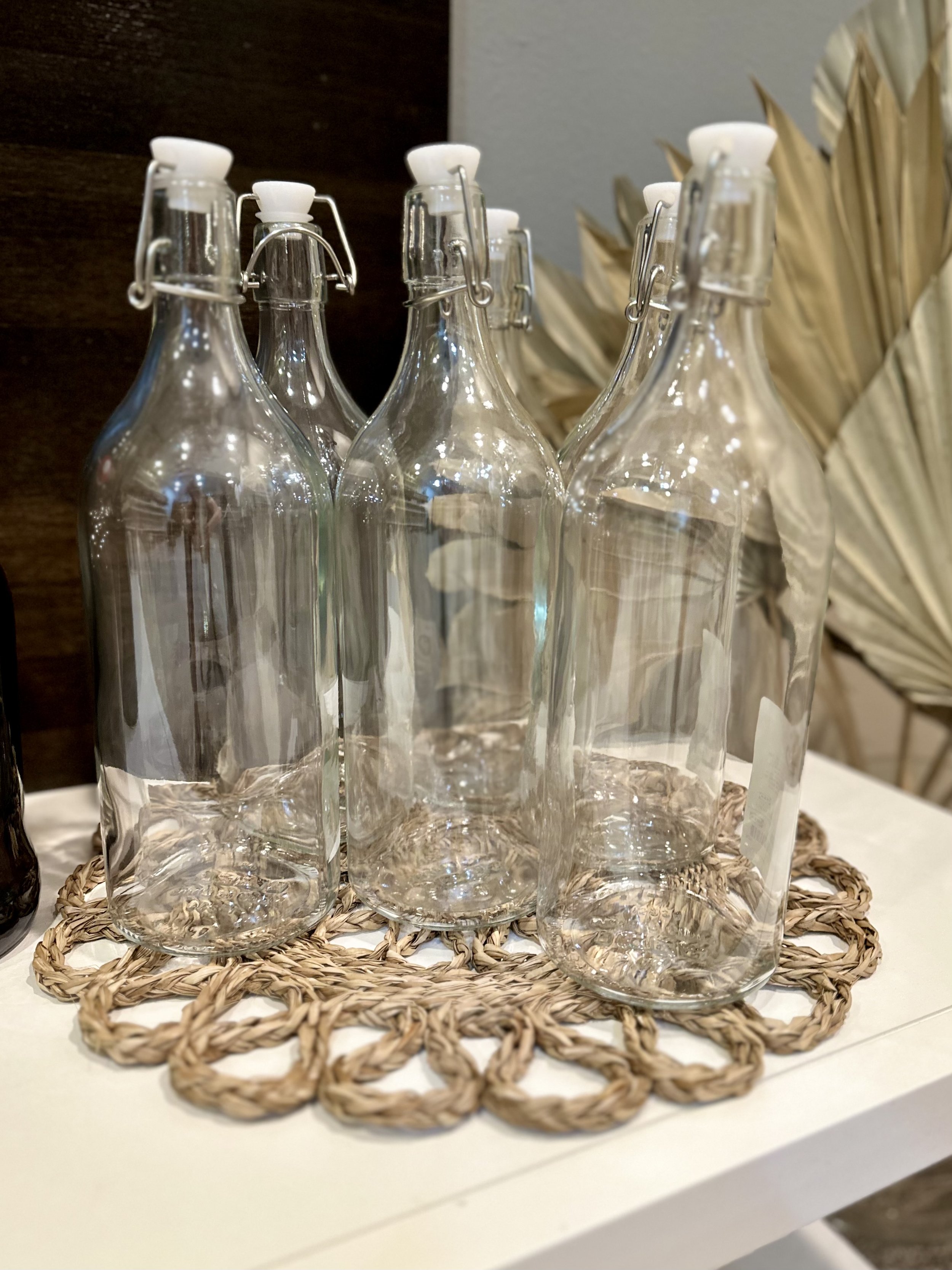 Clear glass bottles with swing-top lids on woven placemat