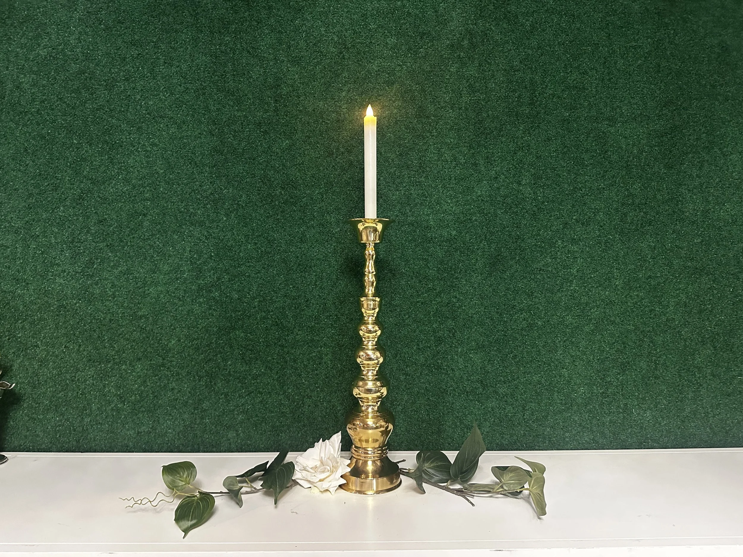 Tall brass column candle holder styled with taper candle and greenery for wedding tablescape