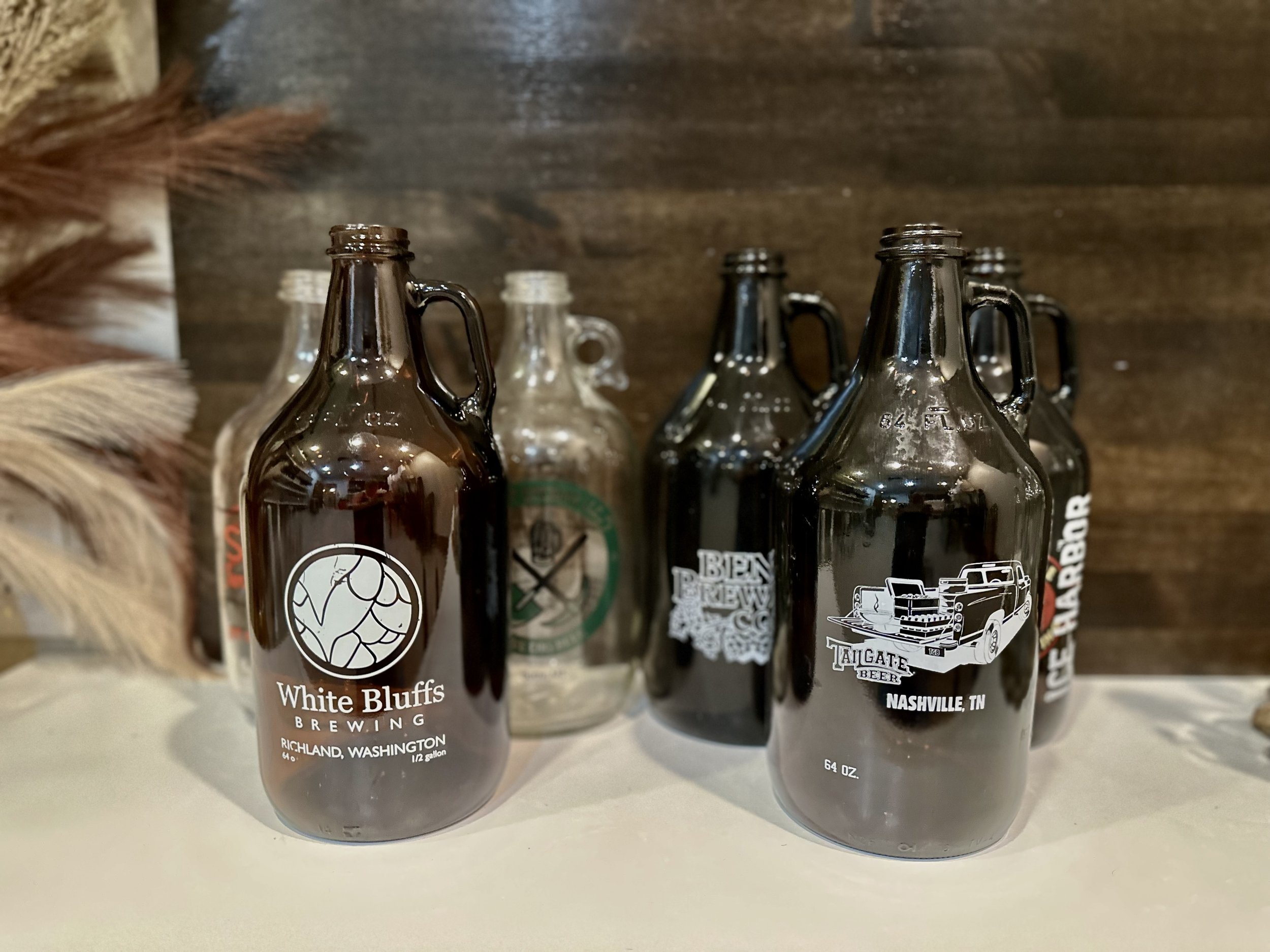 Several beer growlers with various brewery logos displayed in a row.