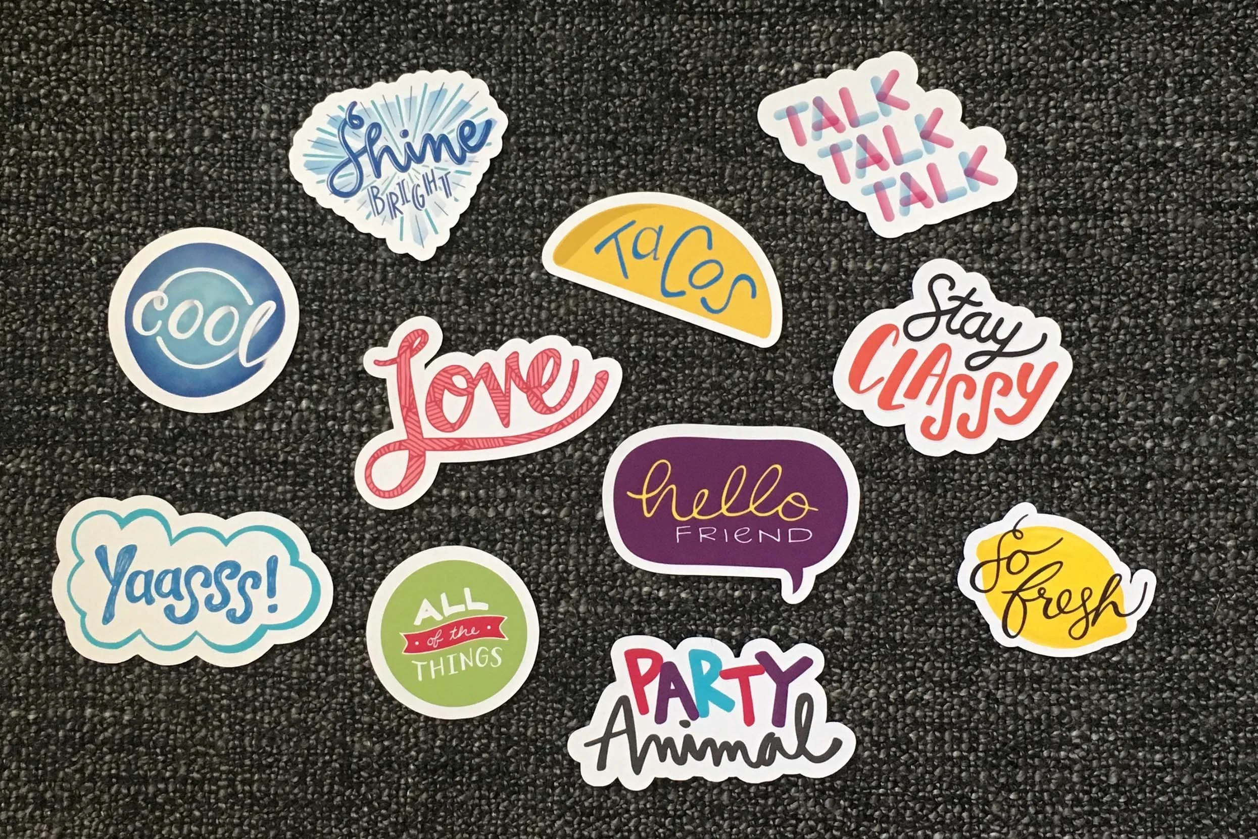 Assortment of colorful sticker featuring hand lettered designs: cool, love, hello friend, lemon fresh, yaass, talk, classy, party animal