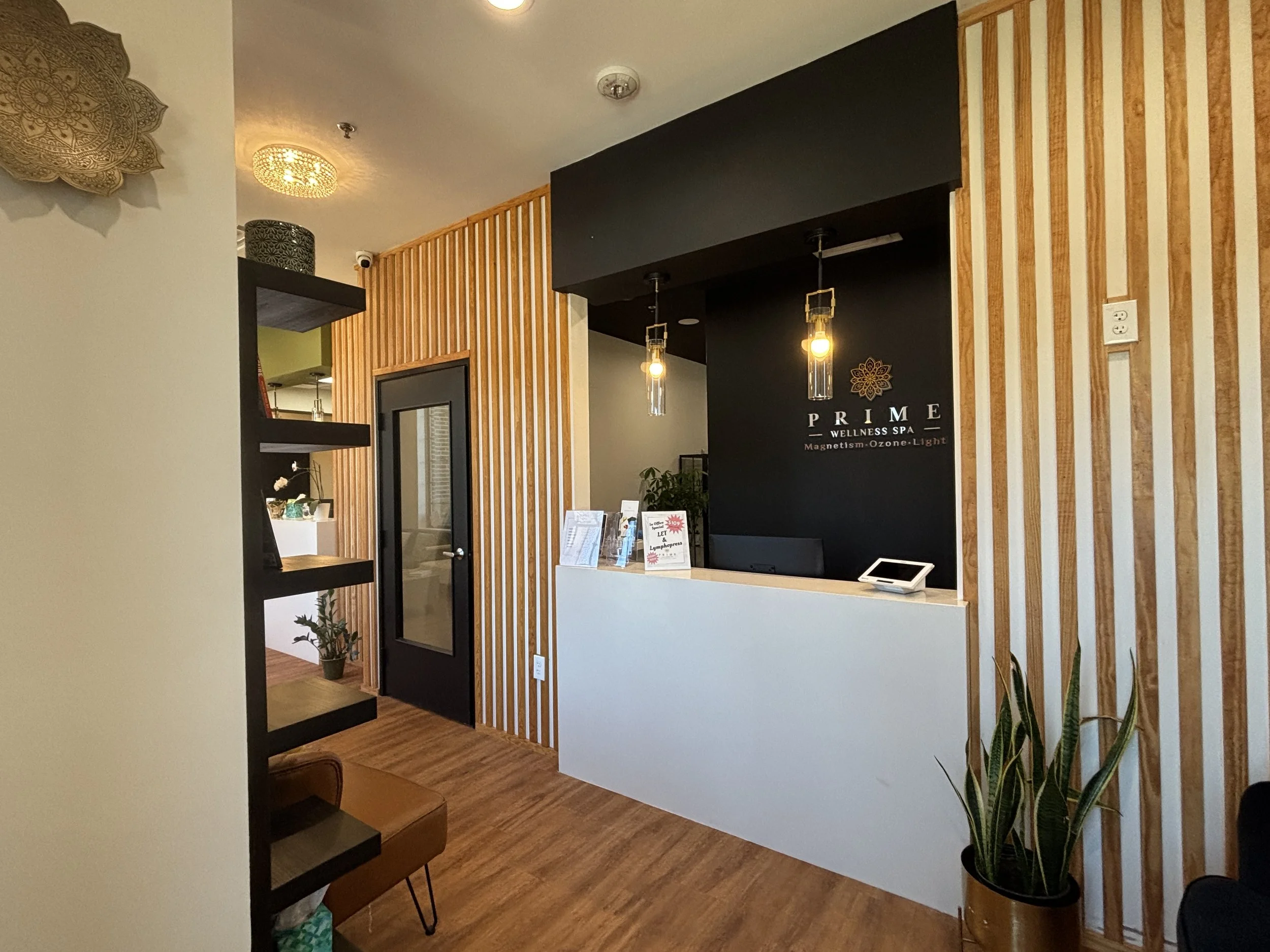 Reception area of Prime Wellness Spa with black and white walls, wooden paneling, and decorative lighting.