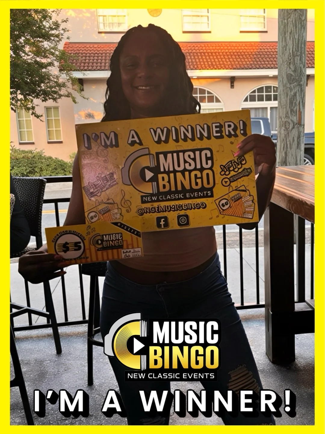 Woman holding a yellow sign that says "I'm a Winner! Music Bingo" at an outdoor venue during sunset.