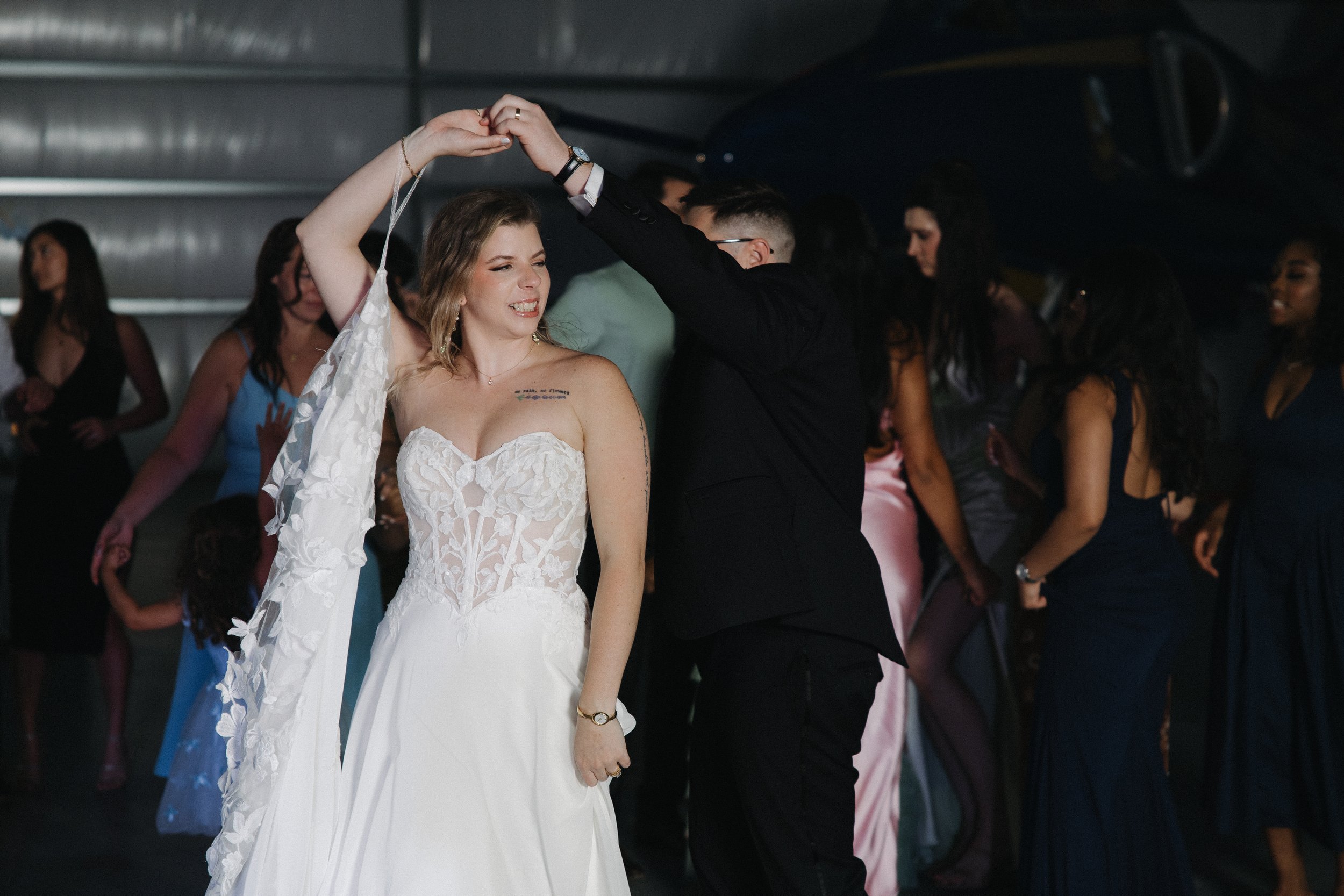 A bride and groom dancing at their wedding reception with guests in the background.
