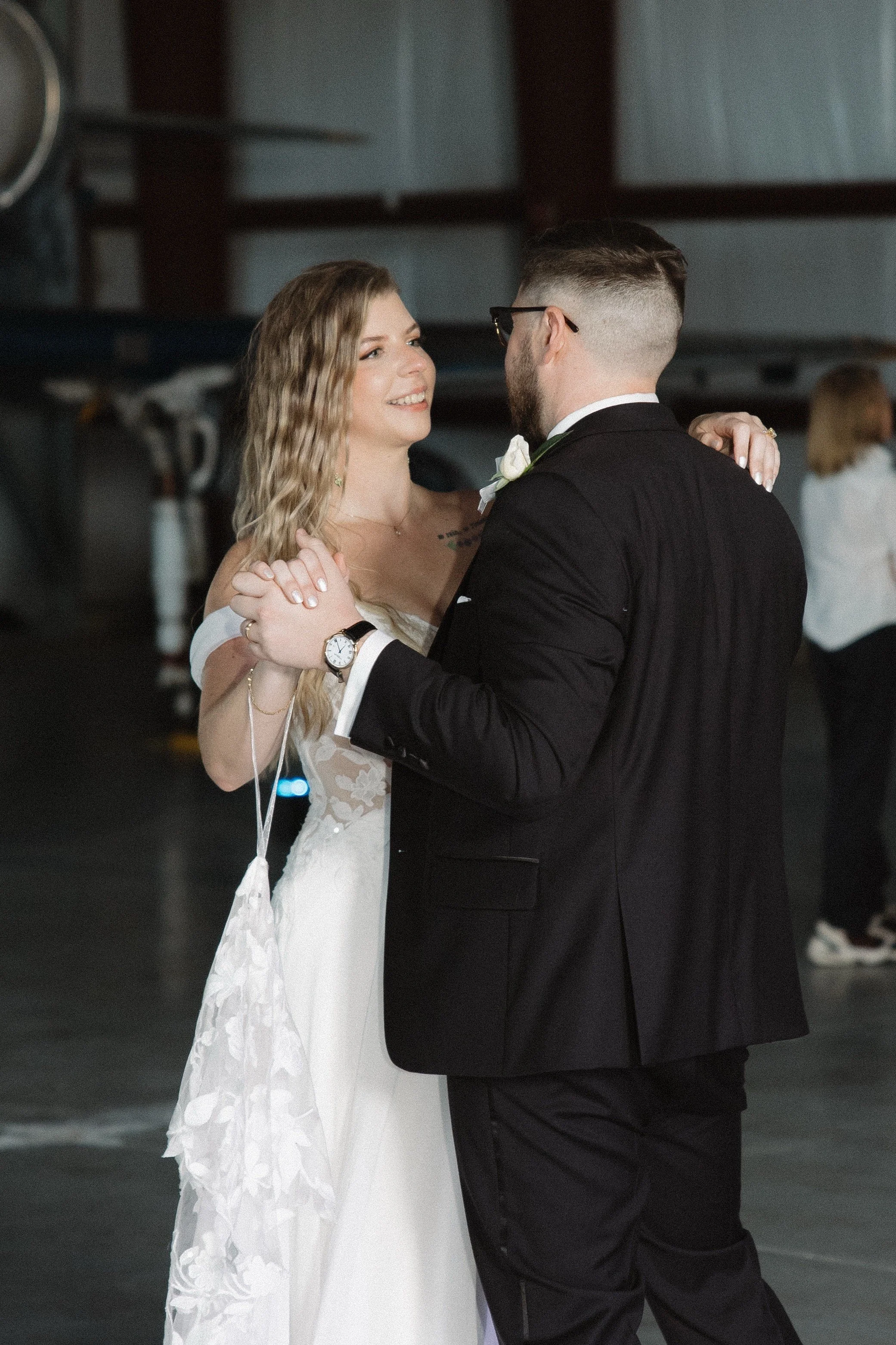 A bride and groom dancing at their wedding reception, gazing at each other with smiles and holding each other close.