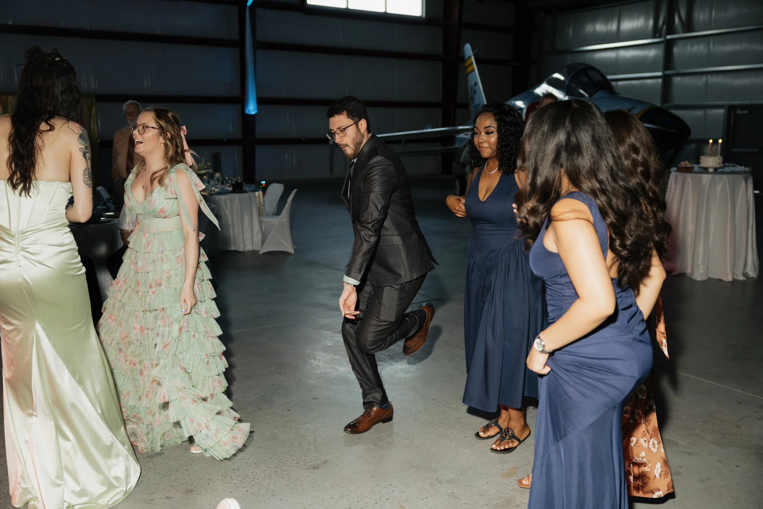 People dancing in a hangar next to a jet aircraft during an event.