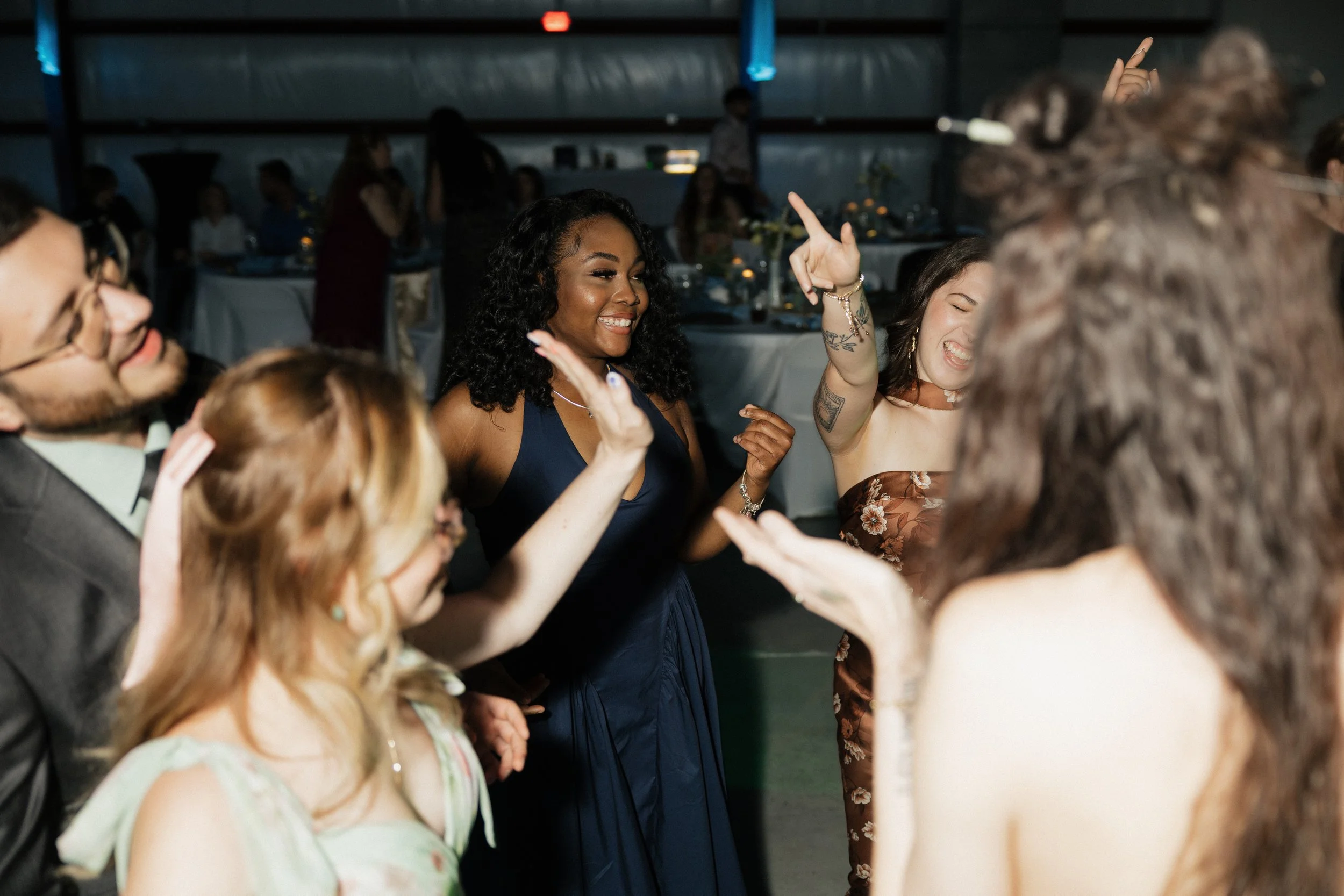 Group of young people dancing and having fun at a party or celebration in a dimly lit venue.