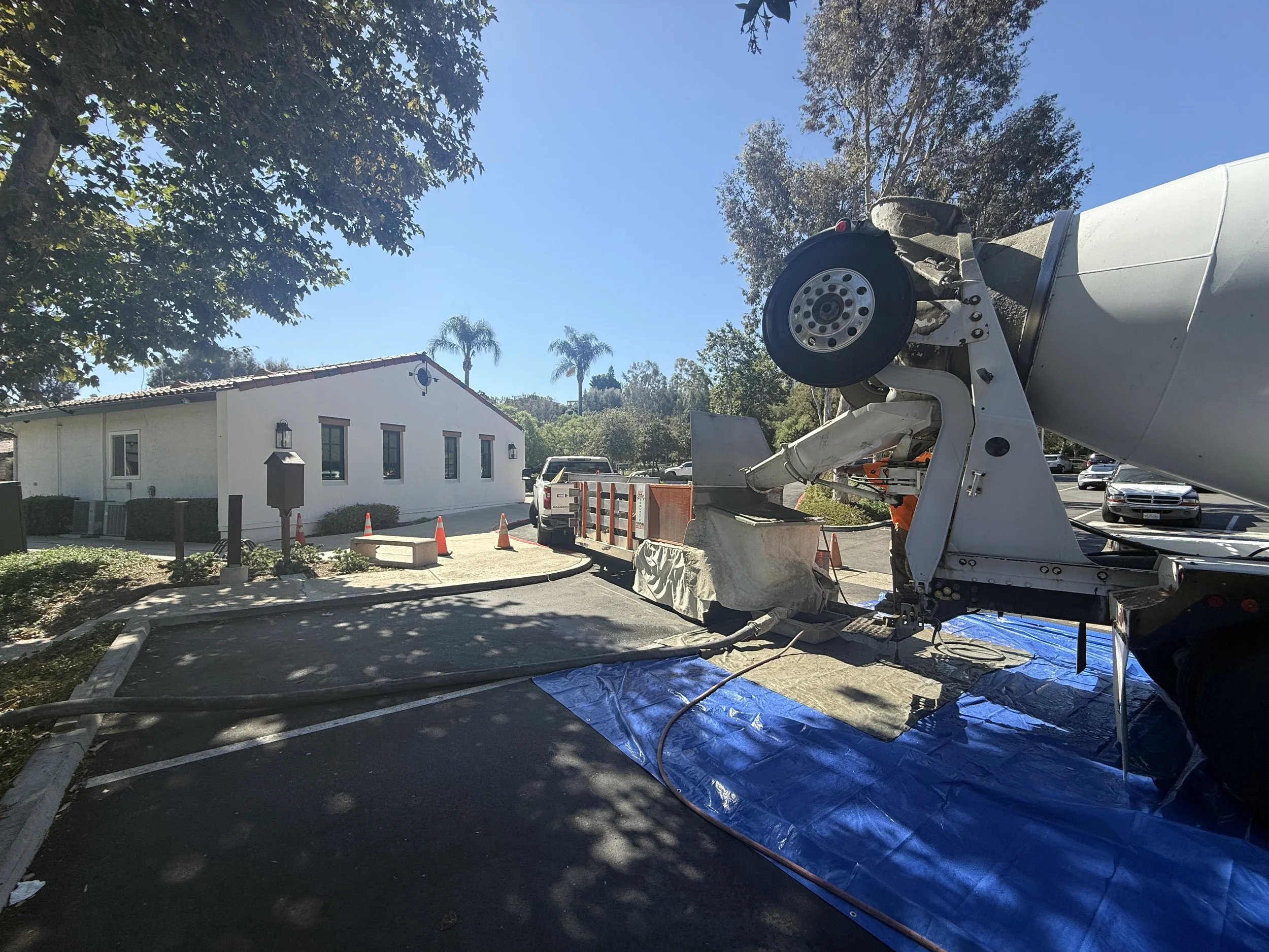 Construction site with a concrete mixer truck pouring concrete, safety cones
