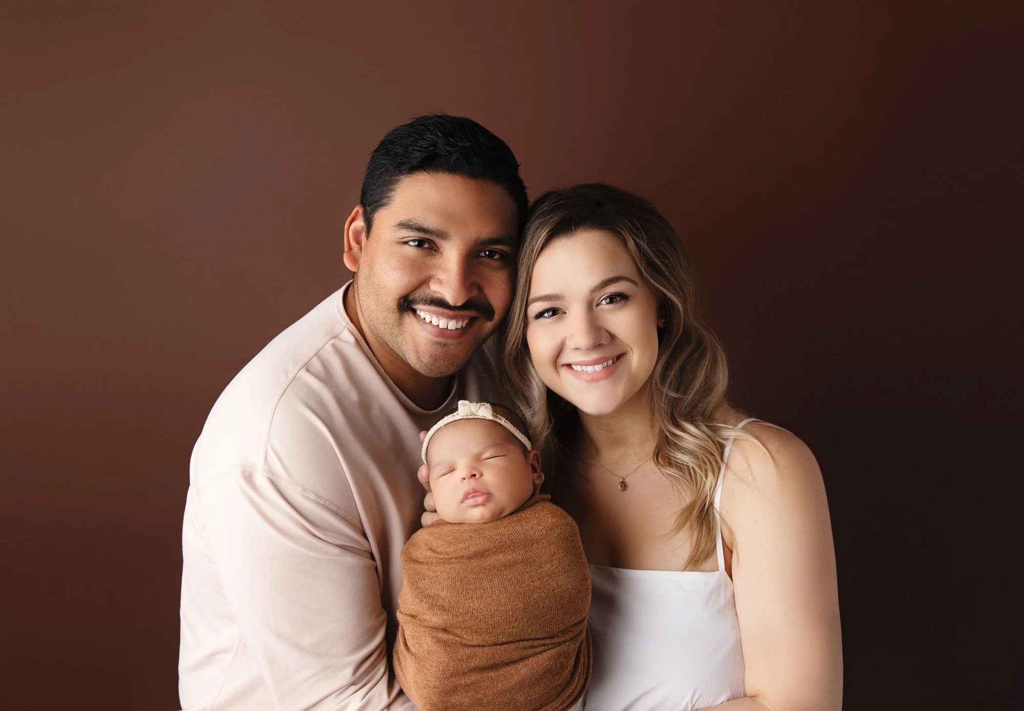 Parents together with their newborn baby during a studio portrait session.