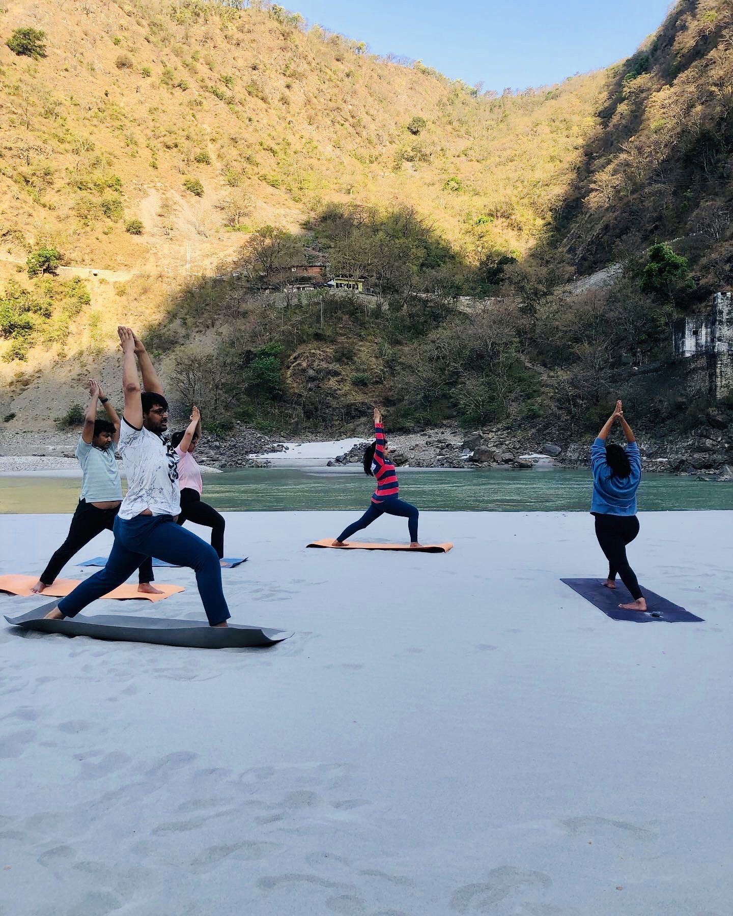 Group practising yoga on a river beach in Rishikesh during the Fitness Bootcamp fitness vacation