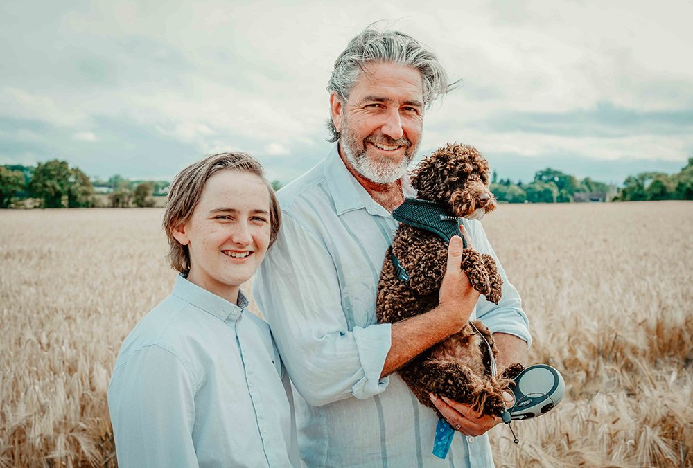son-stands-with-father-holding-brown-dog-in-wheat-field-smiling-together-during-lifestyle-family-shoot-with-buckinghamshire-photographer-david-lefebvre.jpg